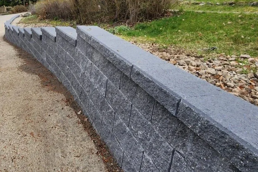 Valley Stone retaining wall installation with charcoal coping for residential landscaping in Salmon Arm, BC