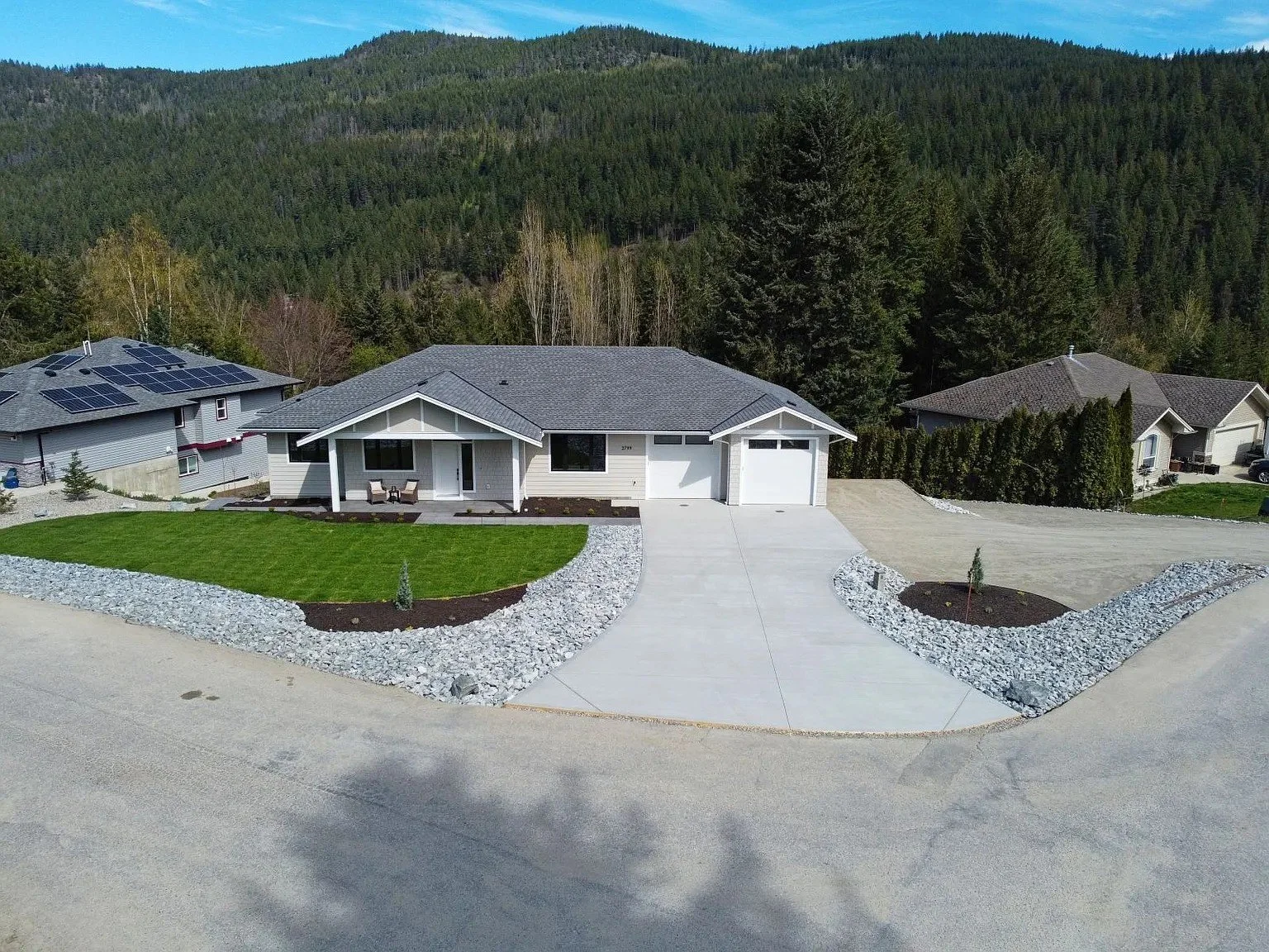 Complete residential landscape transformation with grading, irrigation, decorative stone, planting beds, and custom landscape construction. Blind Bay, BC