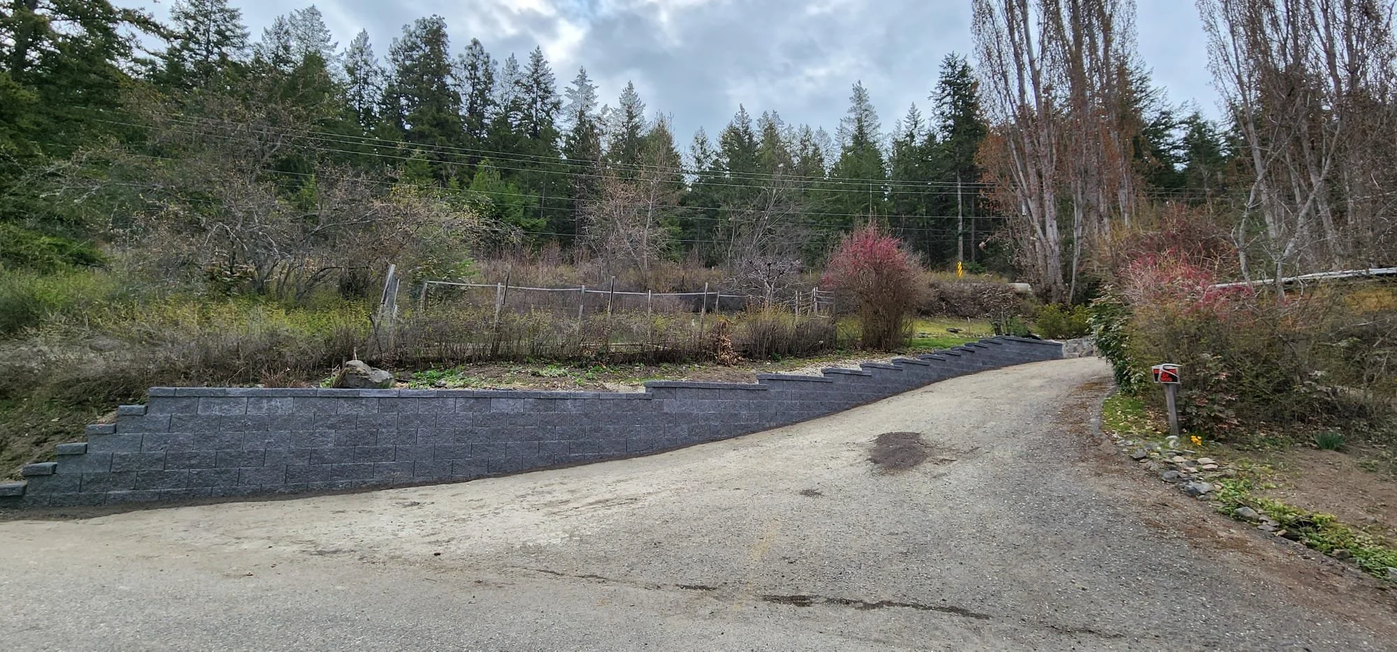 Large retaining wall construction supporting driveway grades and preventing soil movement.