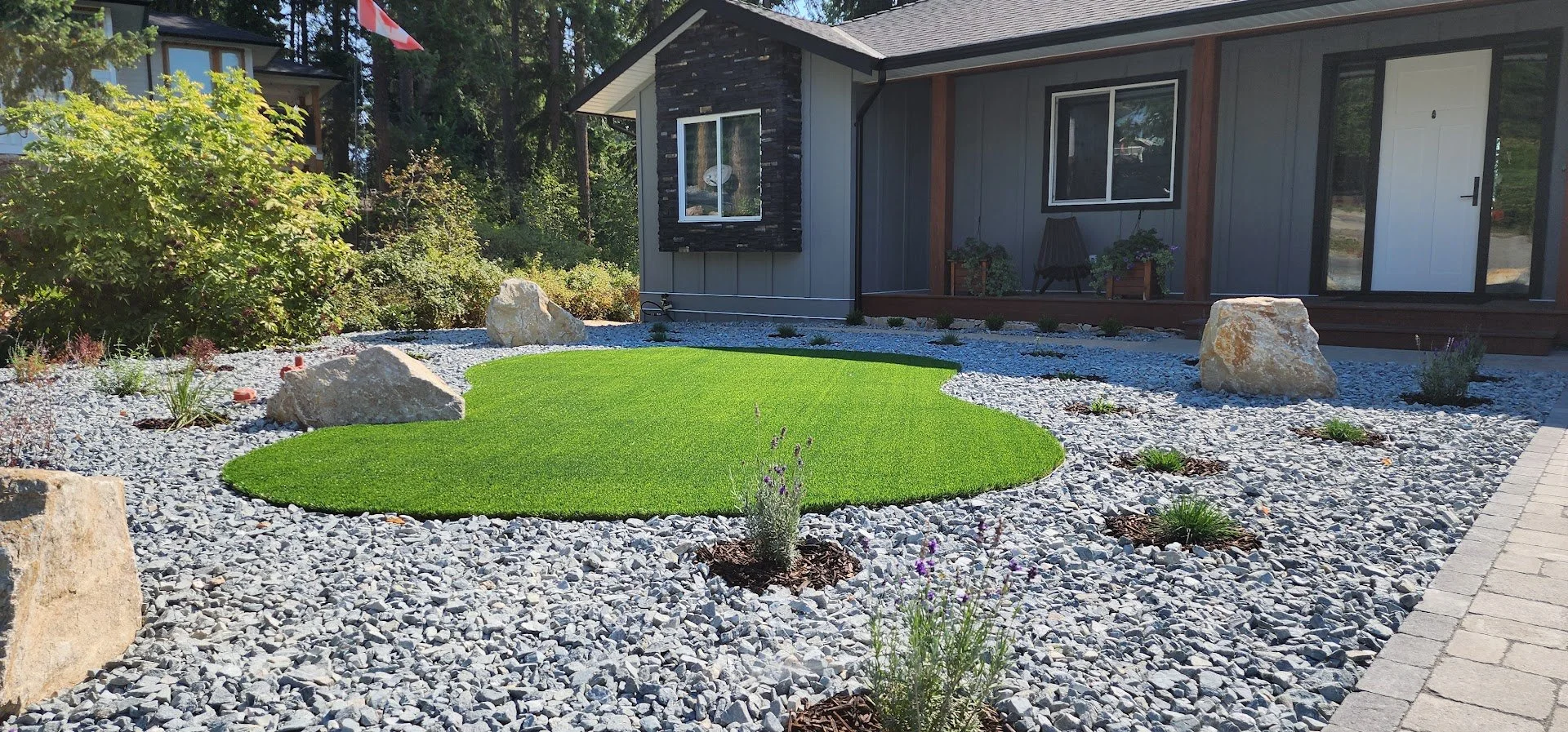 Landscape design with decorative rock and synthetic turf in Blind Bay BC