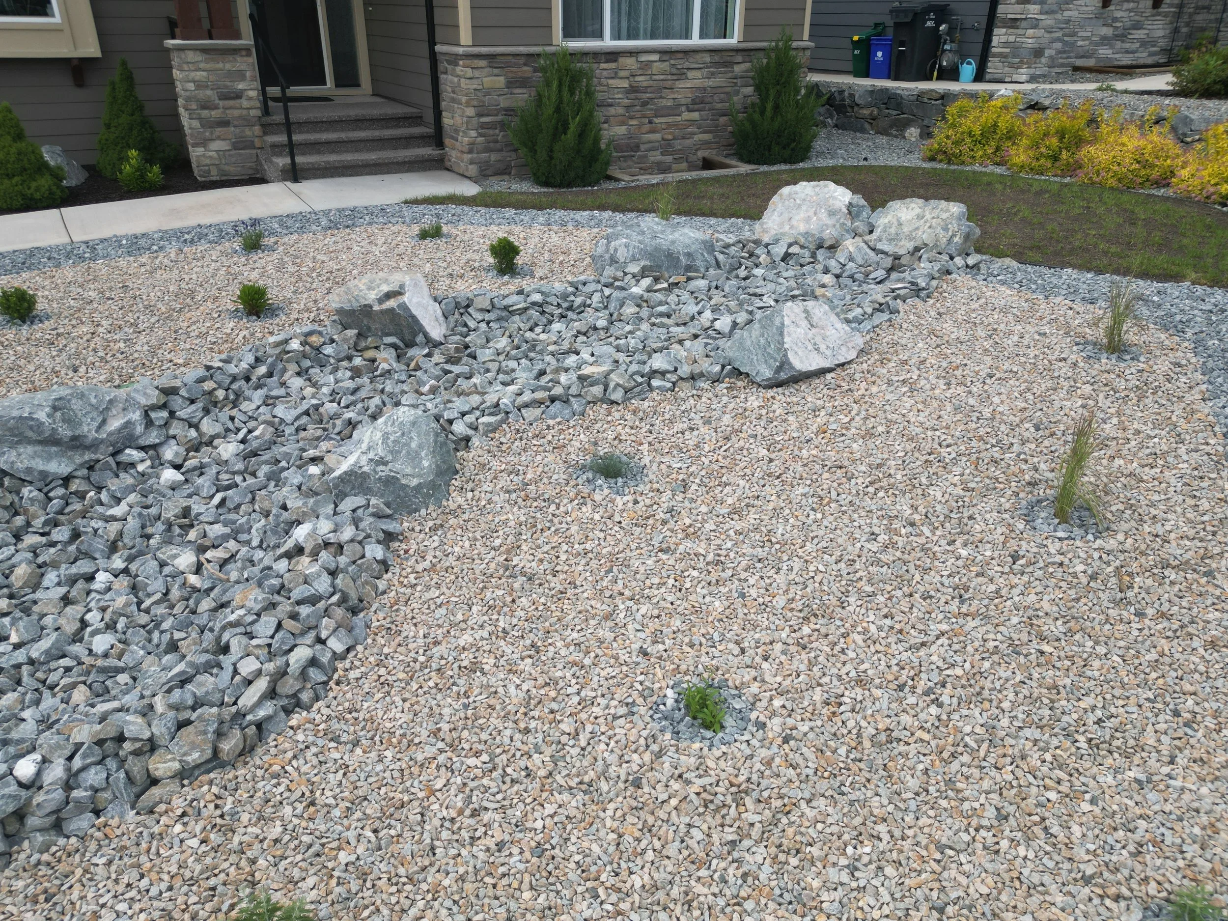 Low-maintenance xeriscape landscape with decorative rock and dry creek bed installation in Armstrong BC.