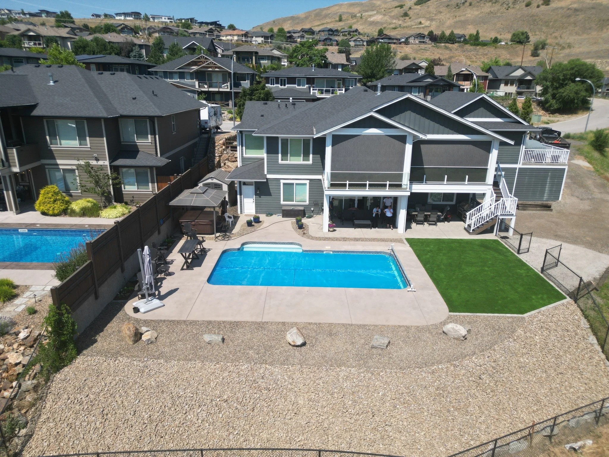 Complete backyard landscaping project featuring a swimming pool, synthetic turf, decorative rock, and landscape construction in Salmon Arm BC.