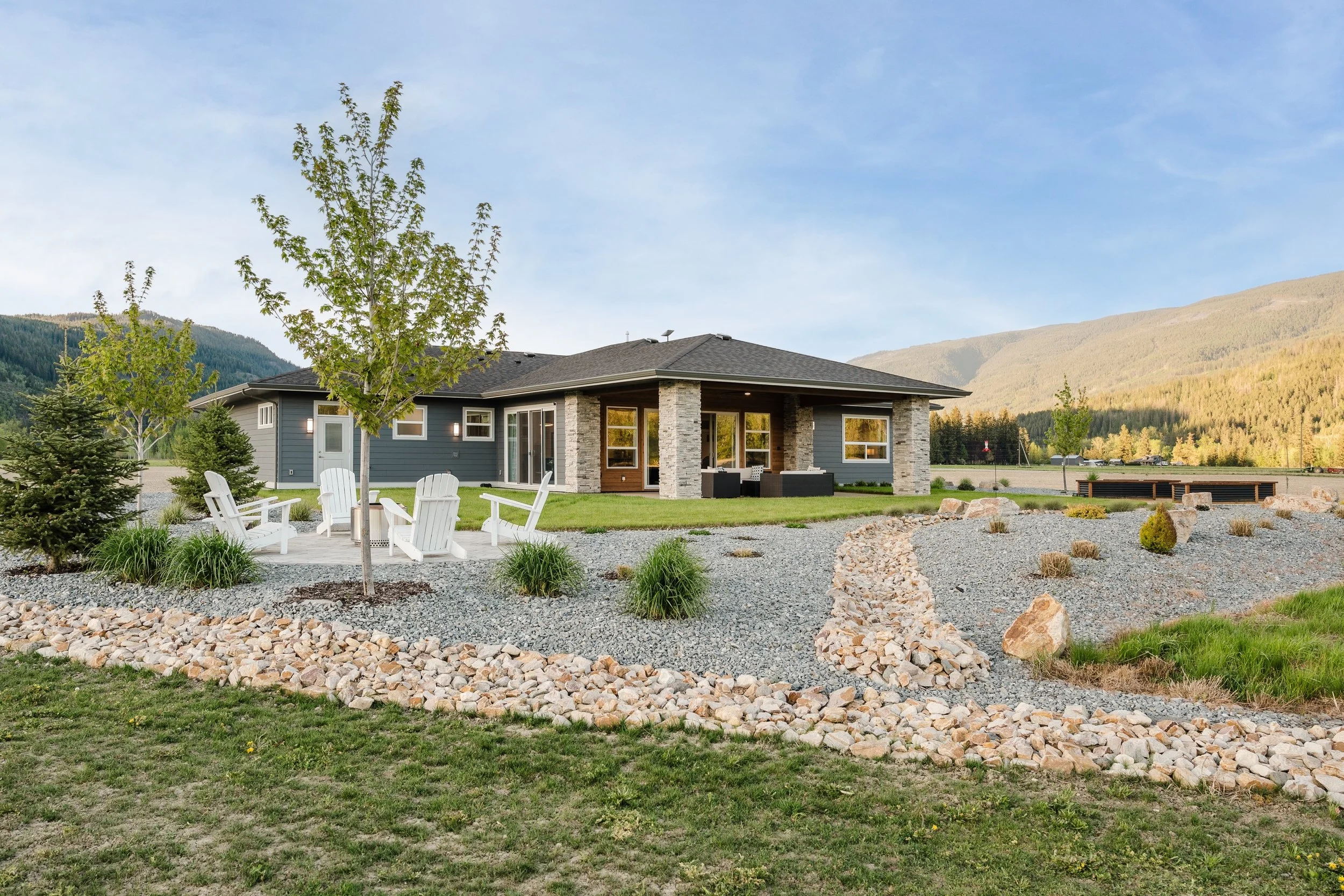 Xeriscape landscaping project in Blind Bay BC featuring a dry river bed, firepit area, decorative rock, grass and low maintenance landscape design by Monarca Landscaping.