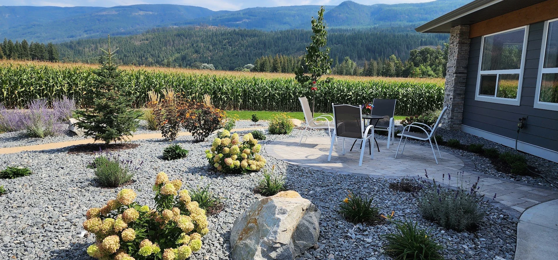 Outdoor living space with decorative rock landscaping and planting beds in Armstrong BC.