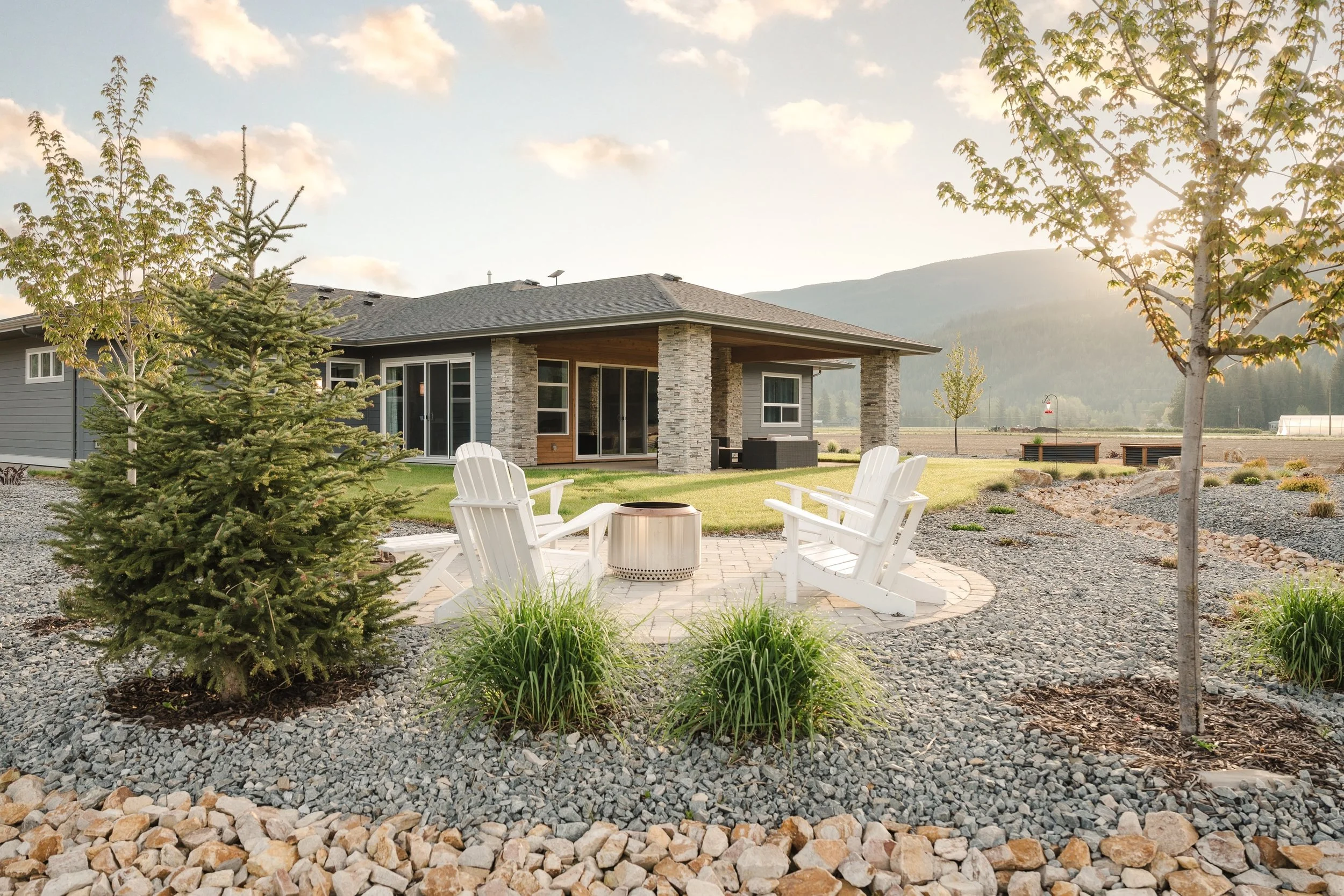 Custom front yard landscaping with decorative rock and planting beds in Armstrong BC.