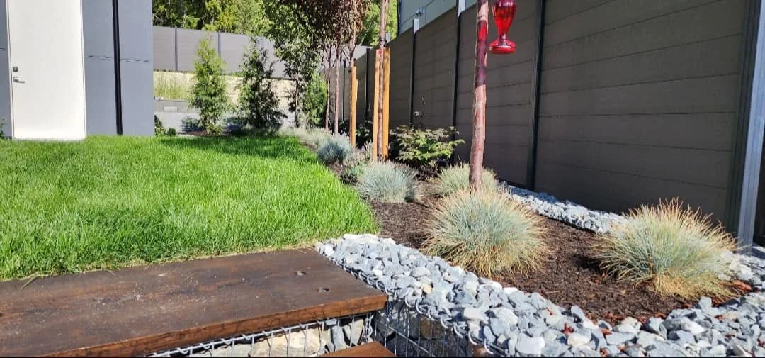Custom landscape installation featuring a walkway, decorative rock, planting beds, and lawn area in Salmon Arm BC.