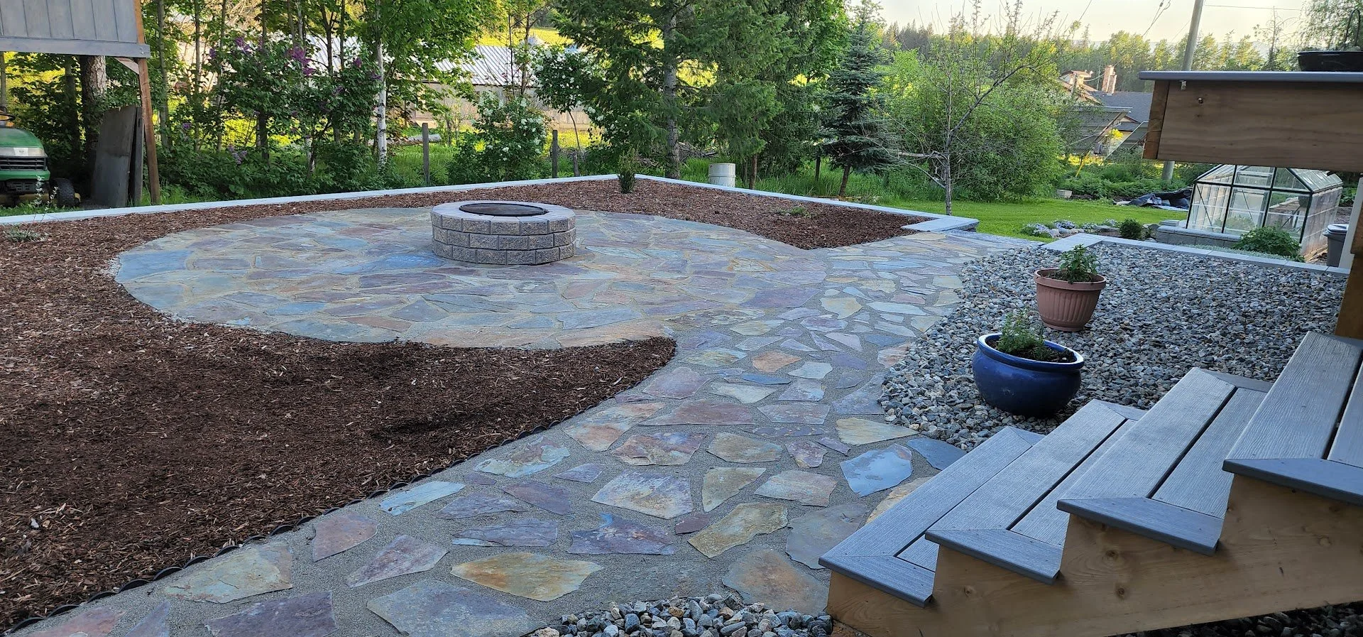 Custom flagstone patio with integrated fire pit and outdoor gathering space in Armstrong BC.