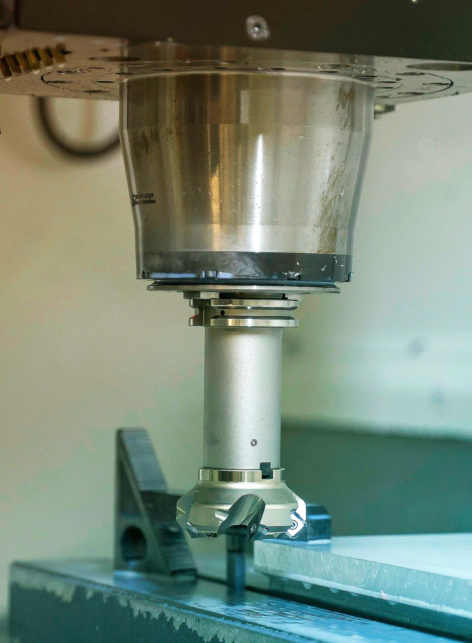 Close-up of a CNC machine tool head with a metal cutting insert, mounted on a worktable.