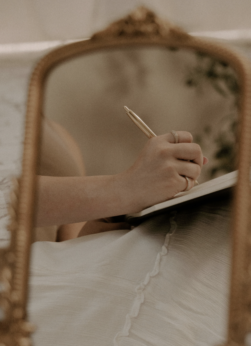 Person writing in a journal with a pen, showing pages with prompts and quotes.