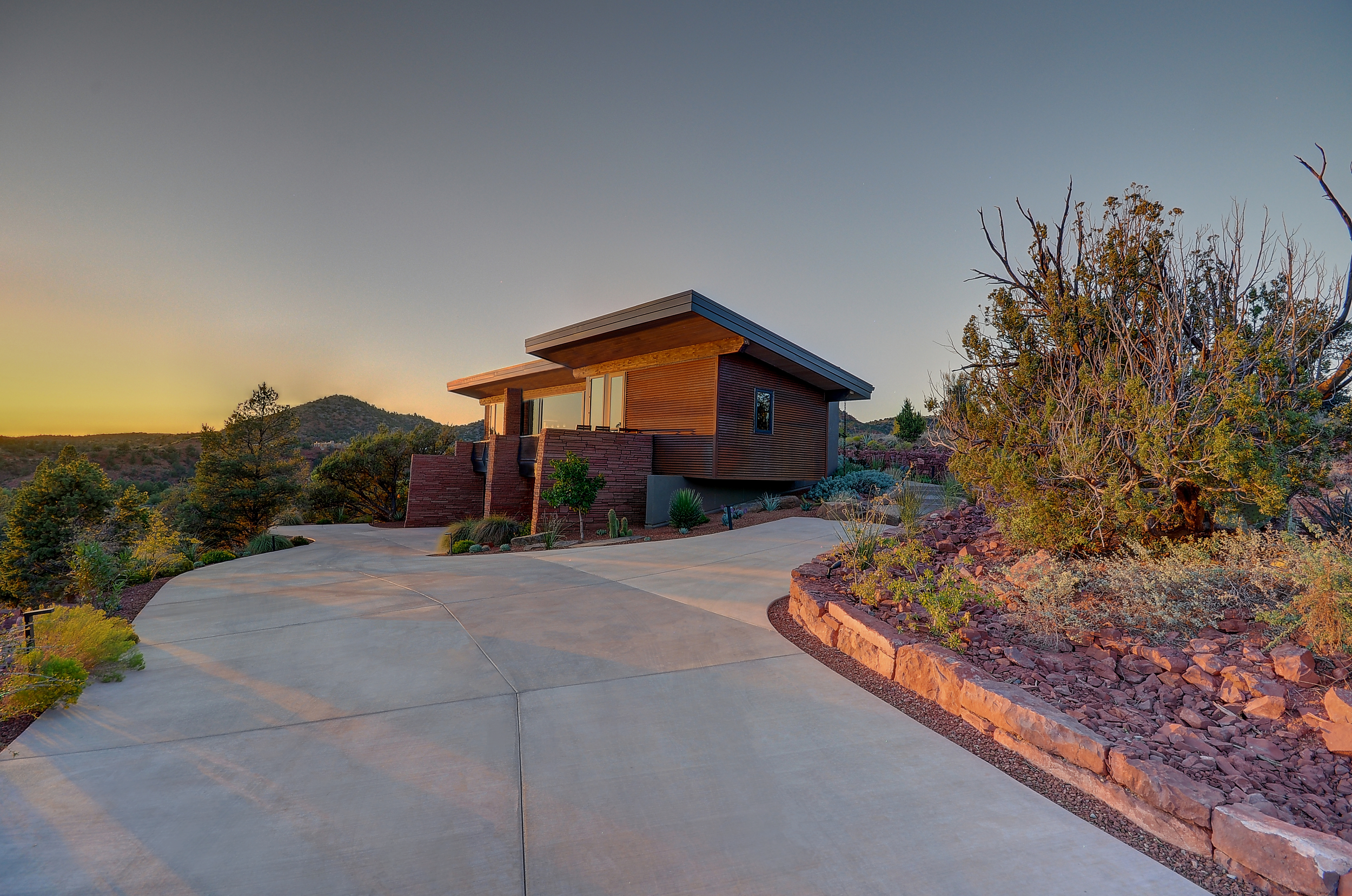 A private residence fitted with rusted metal siding and a pitched roof opening to the gorgeous desert views beyond. 