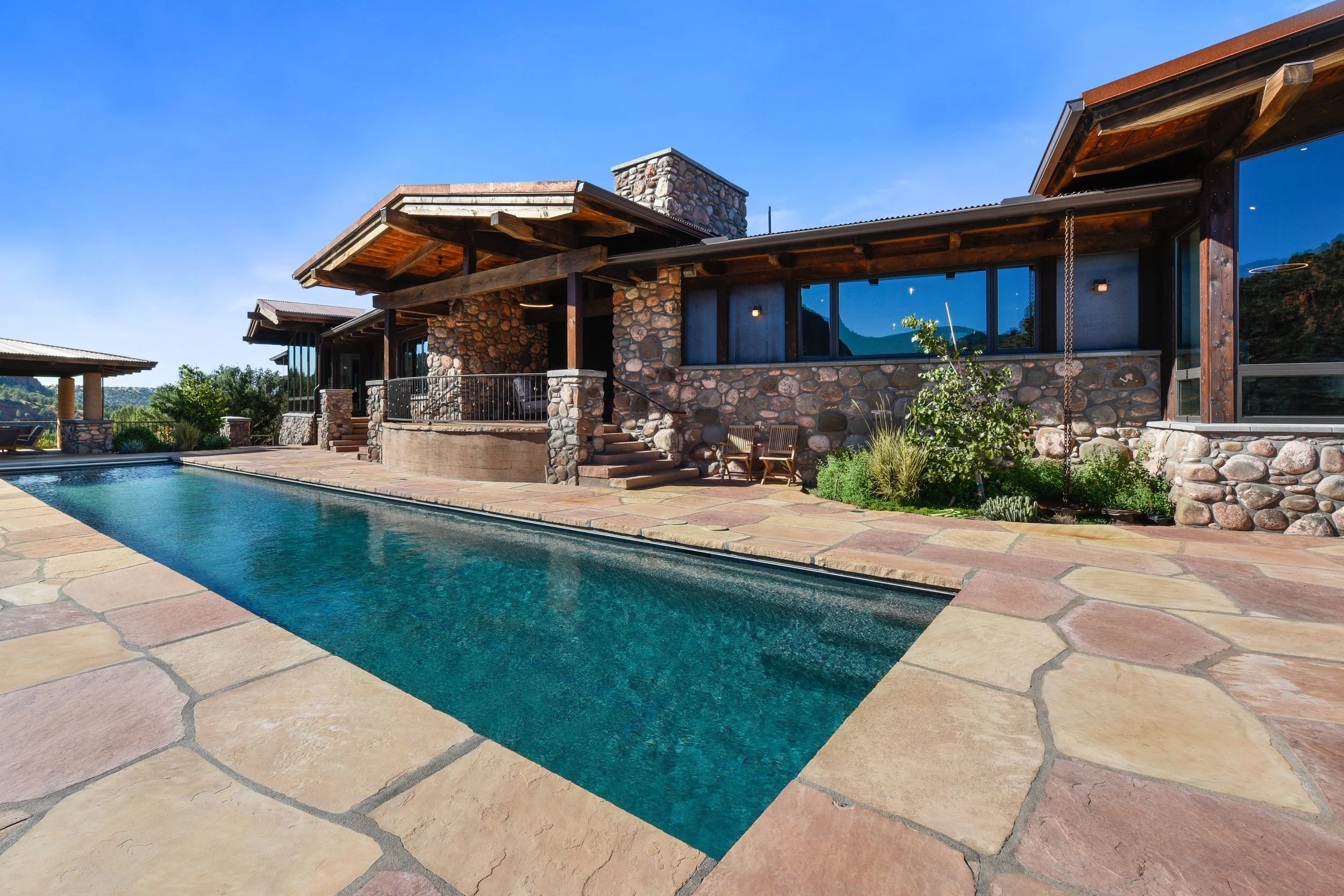 Expansive pool adjacent to a beautiful craftsman home with large windows opening to the valley beyond. 