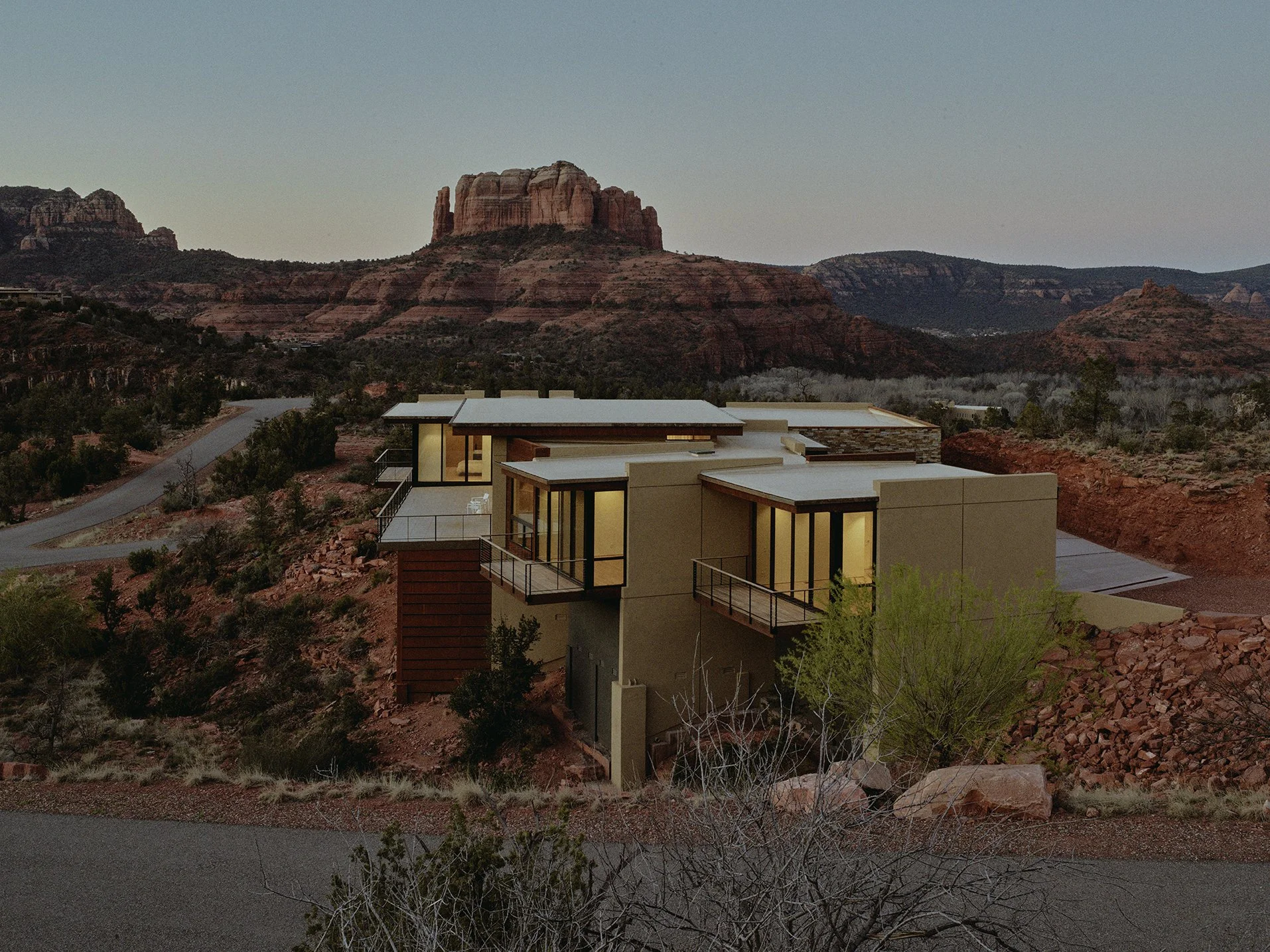 Modern southwestern villa perched atop a sandy slope looking over the red rock formations of Sedona. 