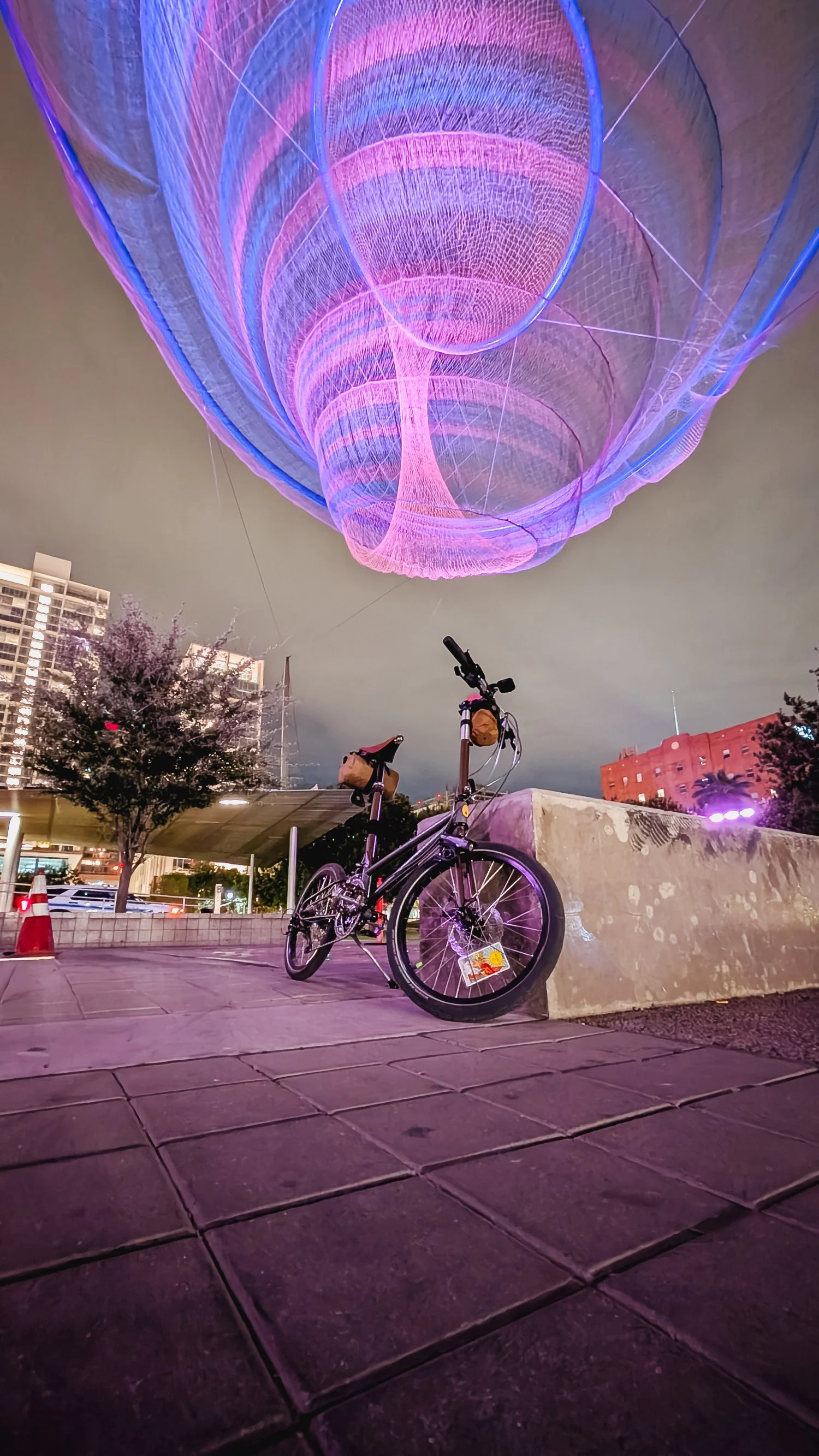 A folding bike posed at night under and art installation