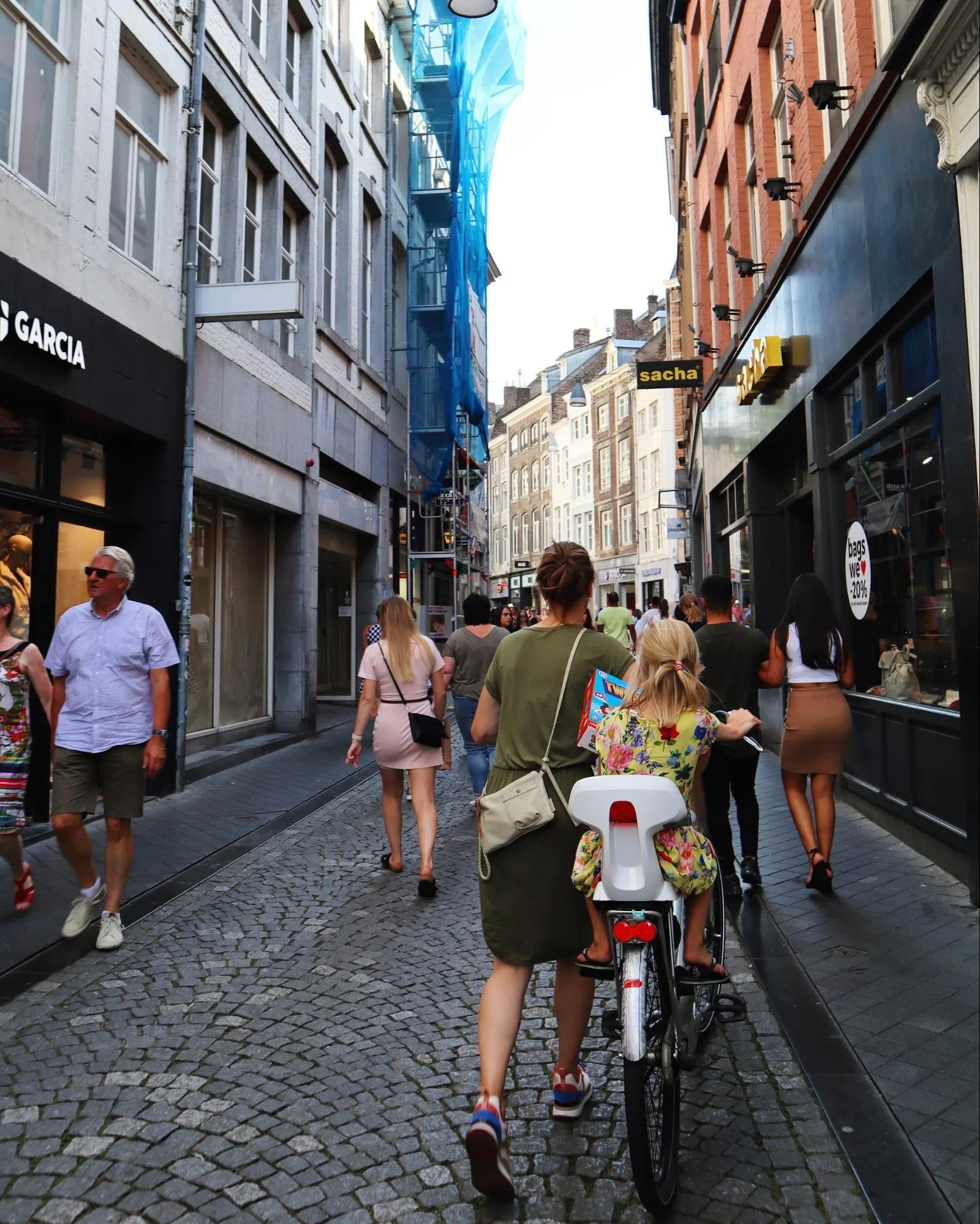 Woman pushing a child on a bike in Amsterdam pedestrian only street