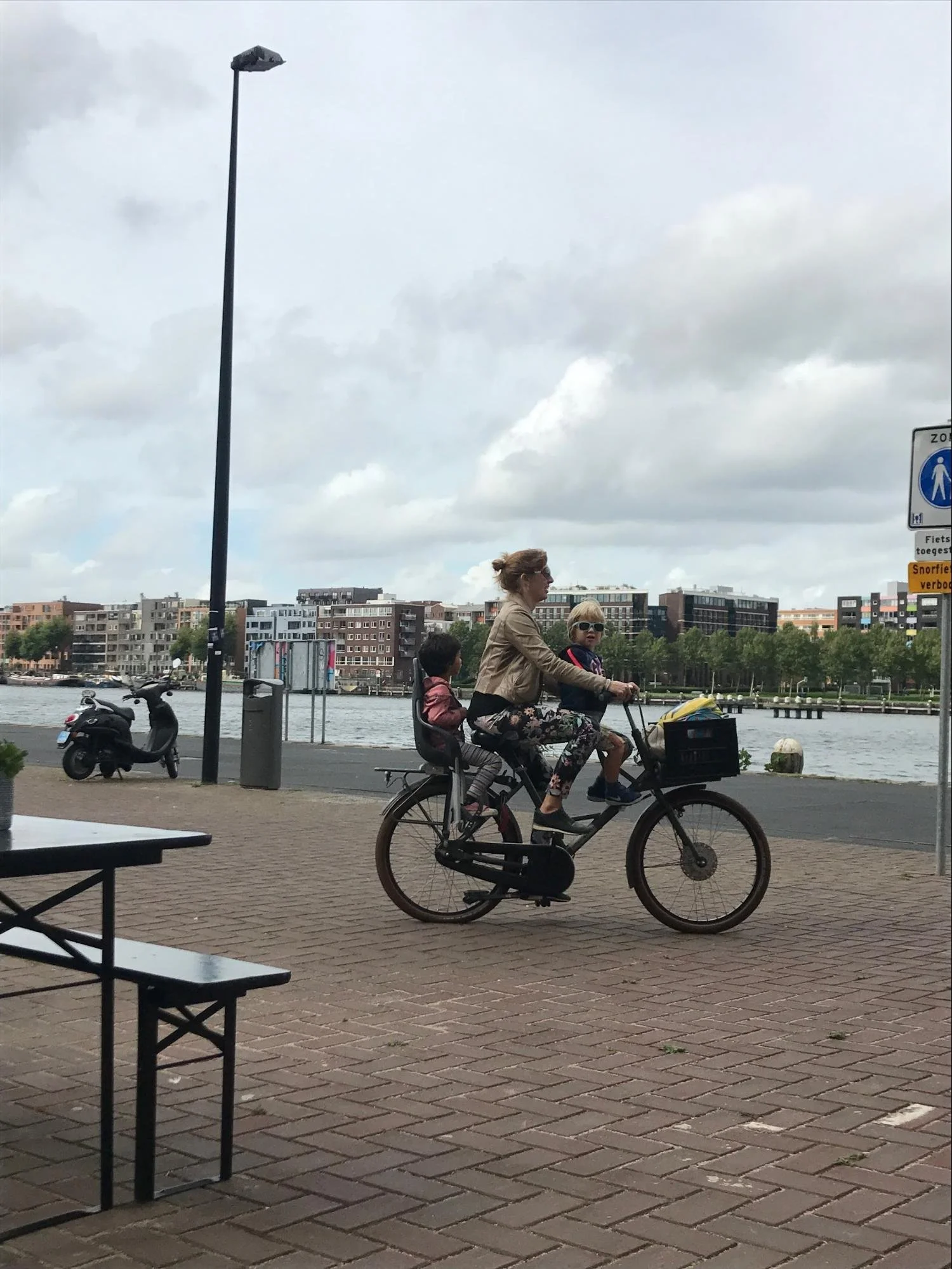 A woman and two childen biking with front and rear mounted seats
