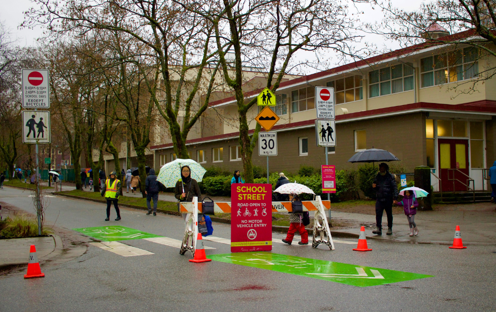 Parents walk their children to school on the Comox “School Street” closed off to cars in Vancouver, BC. Photo taken by Nicole Roach, 2023.
