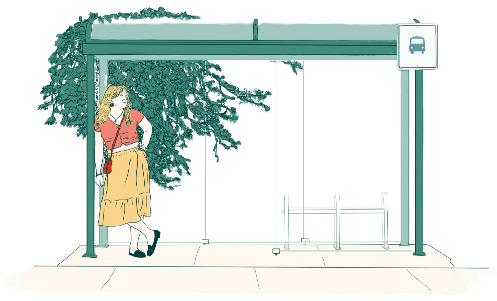 A woman waiting at a bus stop shelter with a large leafy tree behind her.