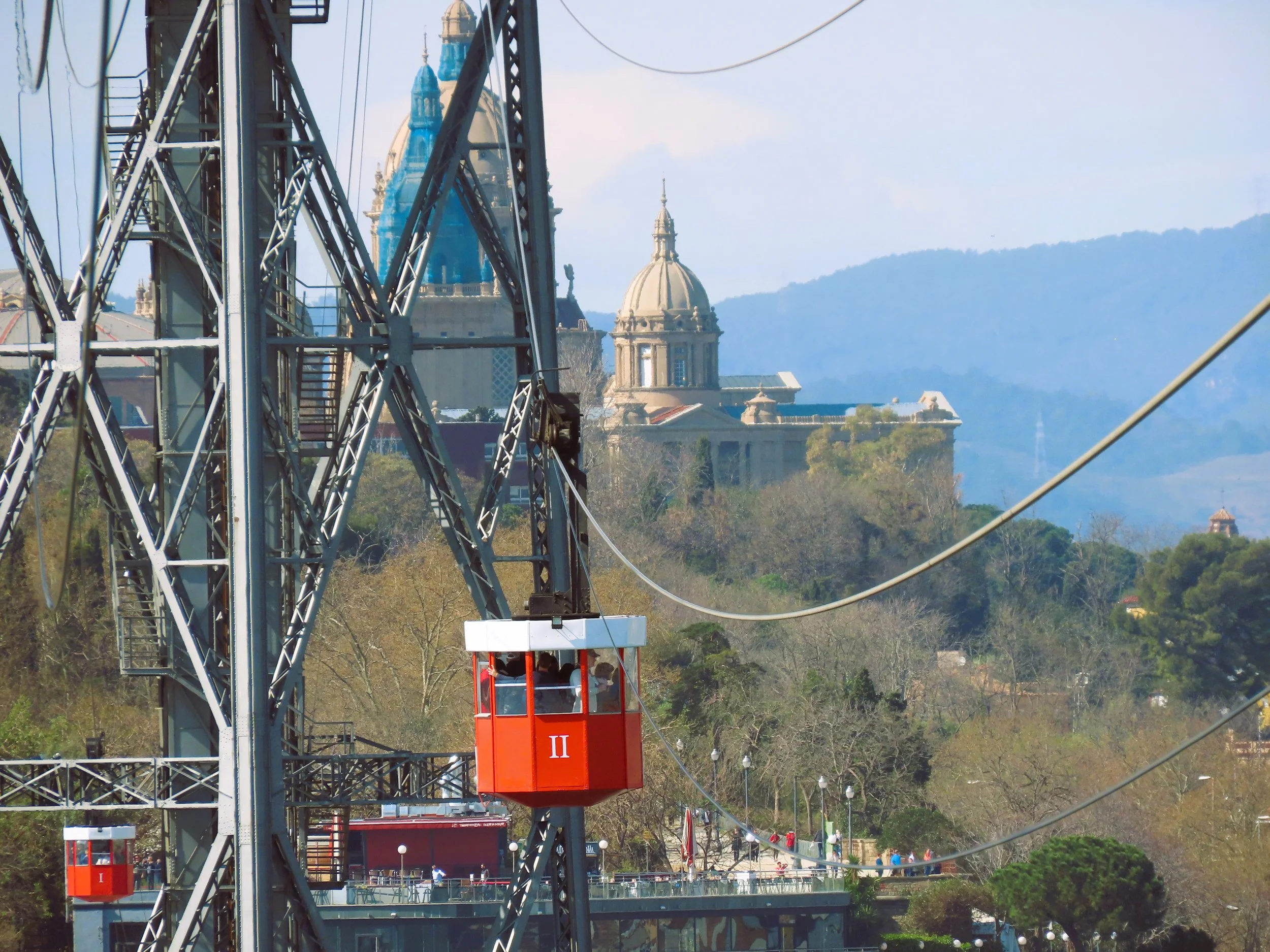 Ruota panoramica con cabine rosse, viste su edifici storici e colline in lontananza.
