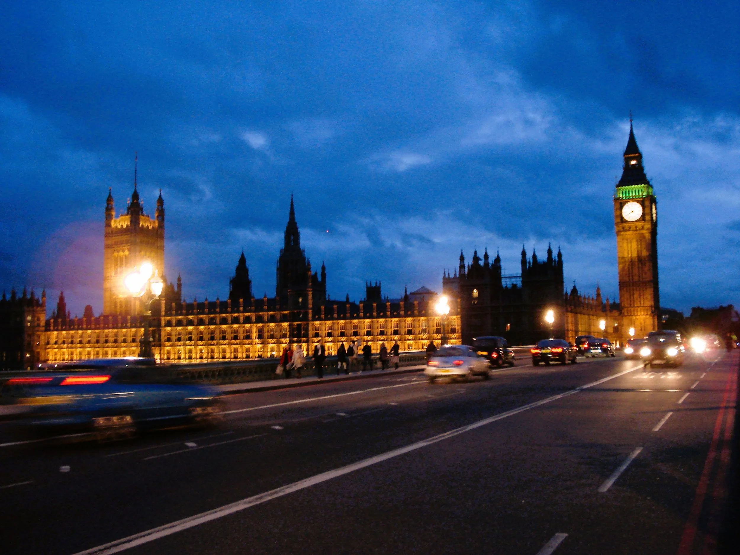 Veduta di Londra con il Big Ben illuminato, veicoli in movimento e un cielo serale blu scuro