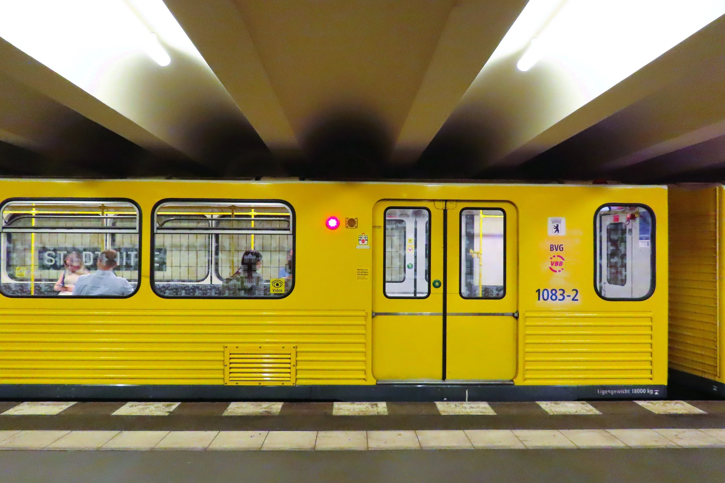 Vagone giallo in metropolitana con alcune persone visibili attraverso le finestre.