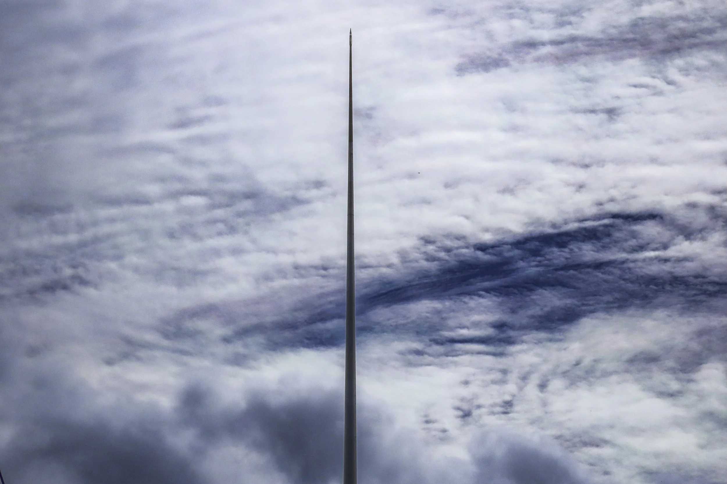 Un'asta lunga e sottile verso il cielo con nuvole sparse.