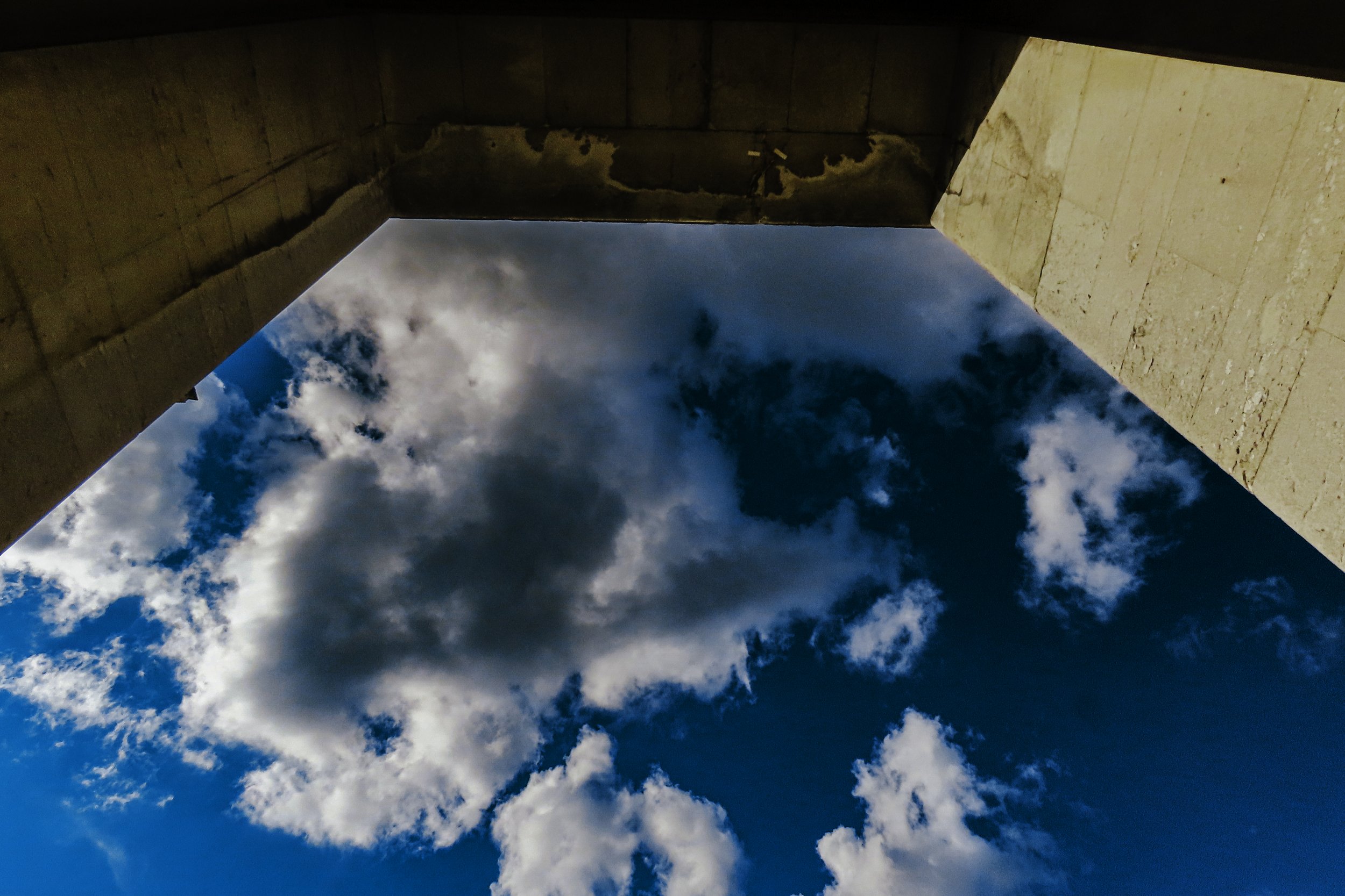 Vista dal basso di una struttura architettonica con il cielo con nuvole sopra.
