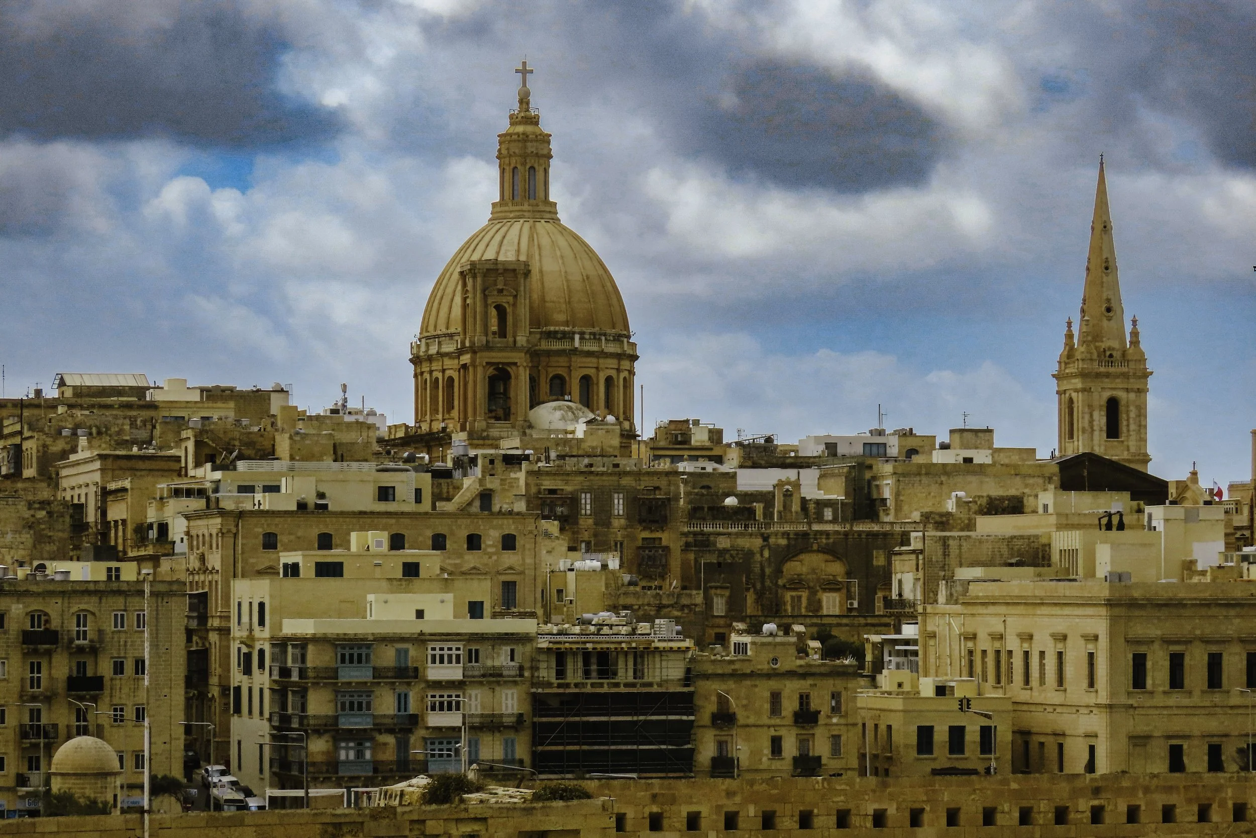 Panoramica della città di Malta con una grande cupola e un campanile visibili contro un cielo nuvoloso.