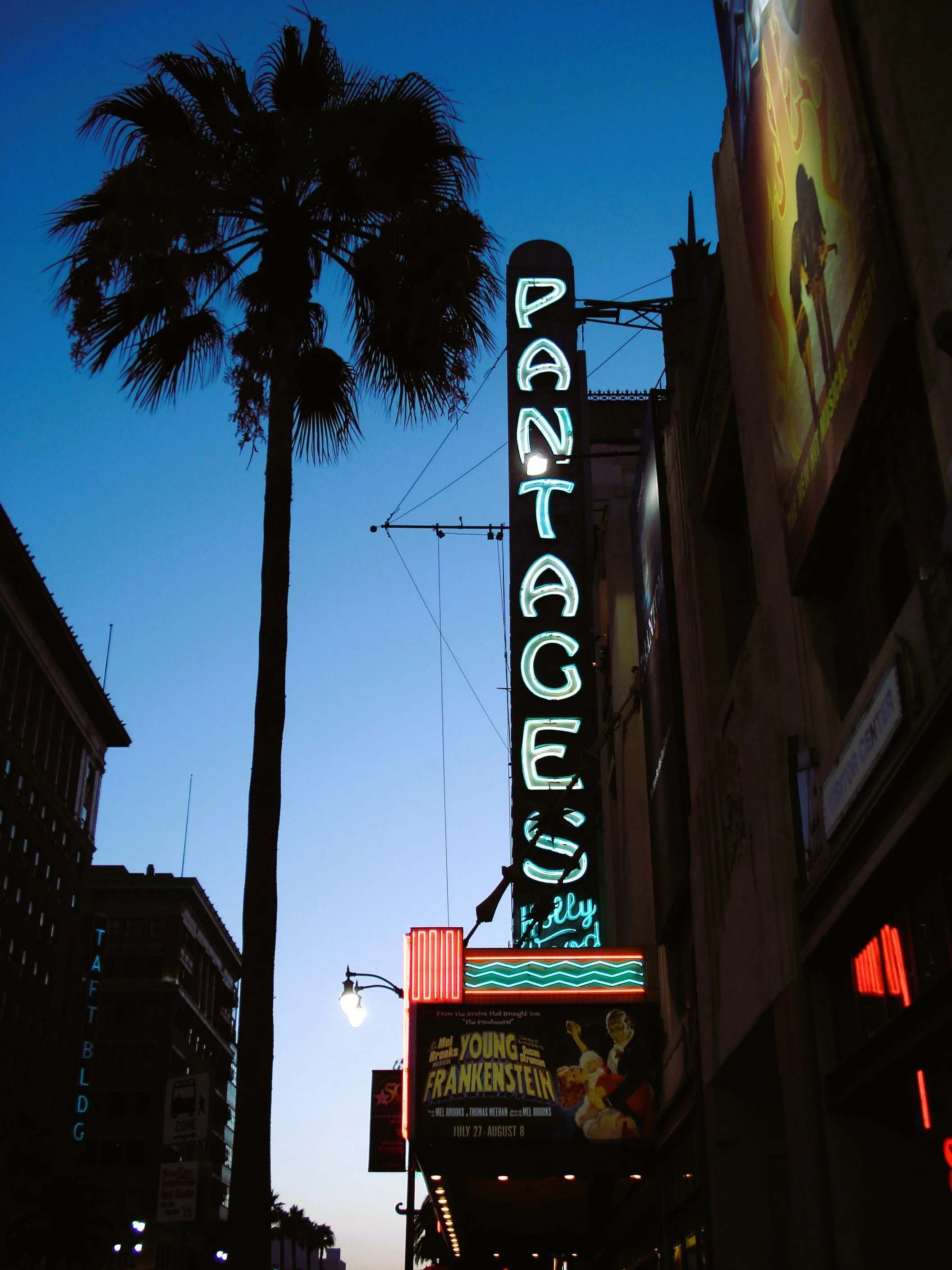 Segnale luminoso che dice 'Pantage' e un poster di uno spettacolo teatrale 'Young Frankenstein' nella sera
