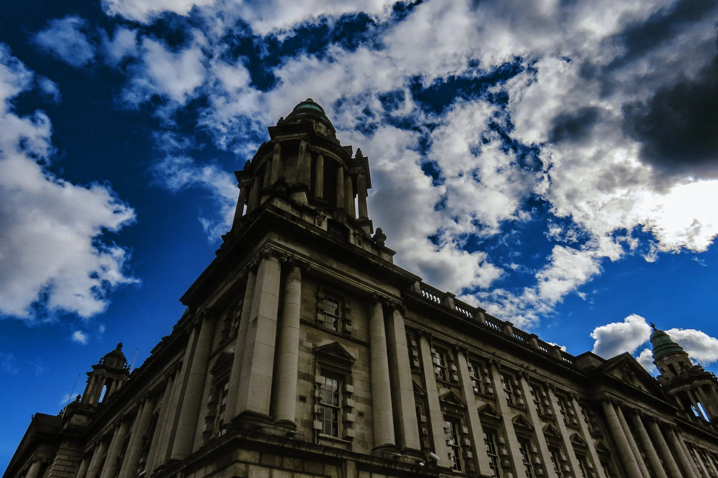 Vista di un edificio storico con colonne e torri sotto un cielo con nuvole e sole