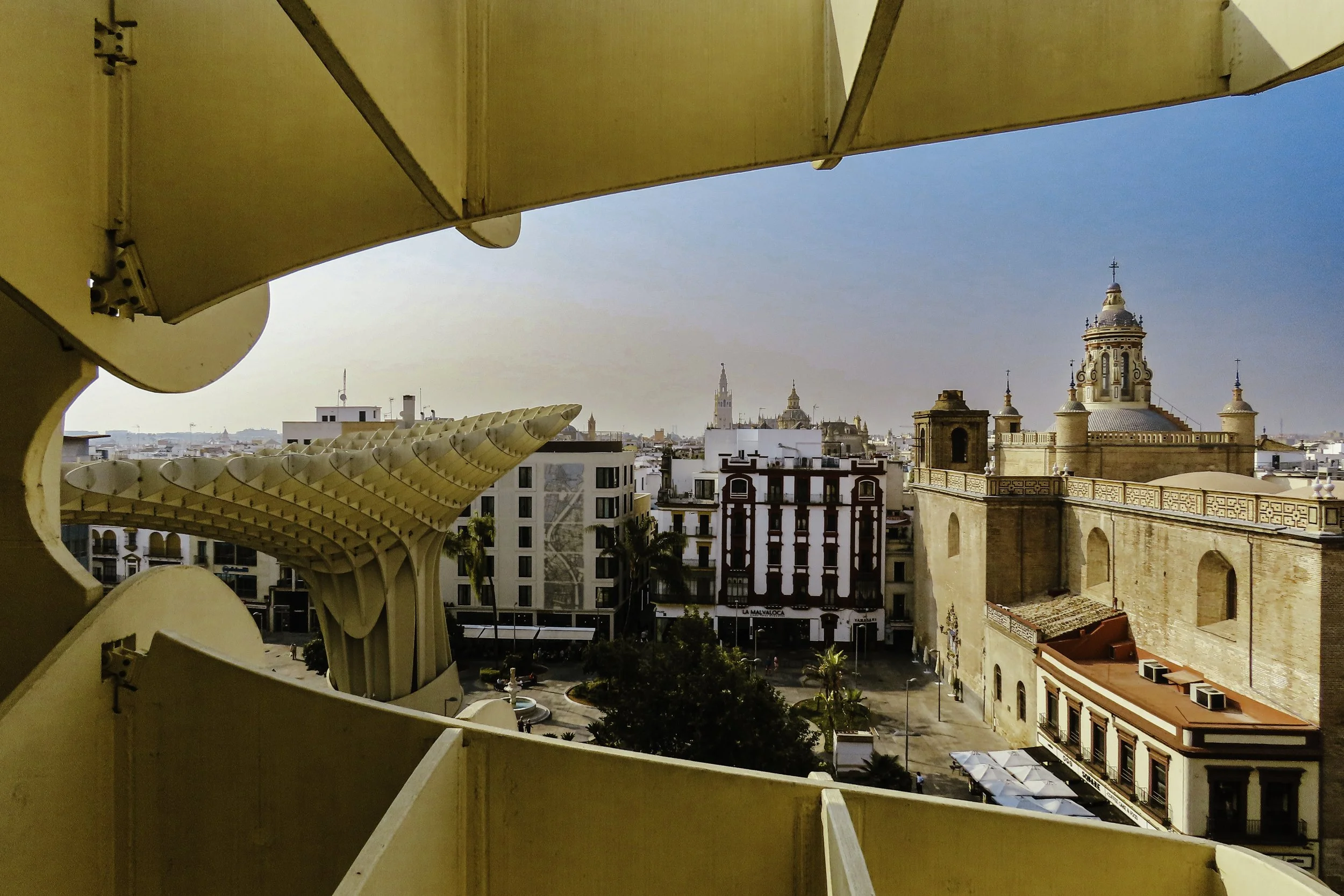 Vista di un'area urbana vista dal balcone, con edifici e chiese storiche, tra cui la Torre de la Malva-rosa, sotto un cielo azzurro e sereno.