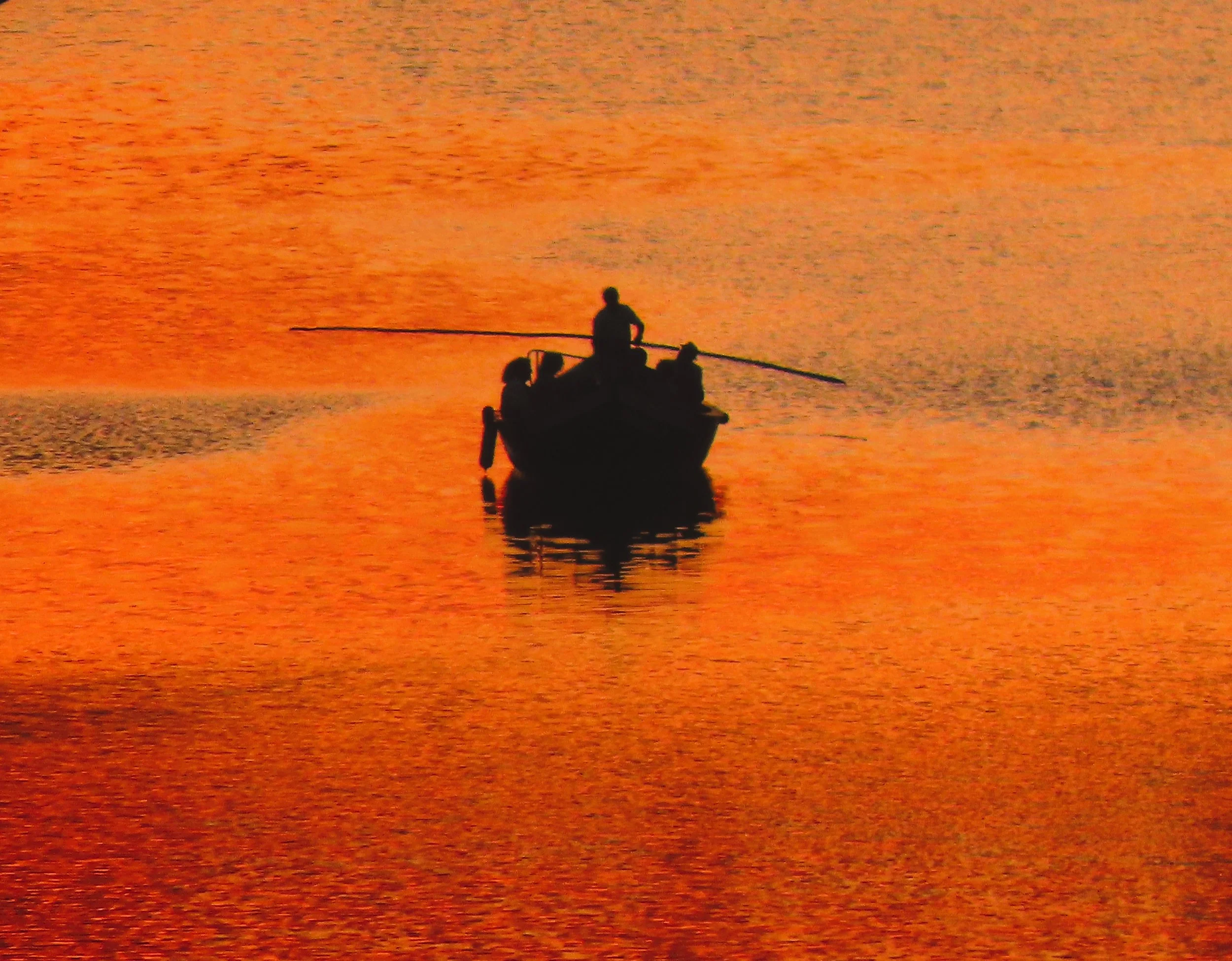 Barca a vela in mare al tramonto con riflessi arancioni
