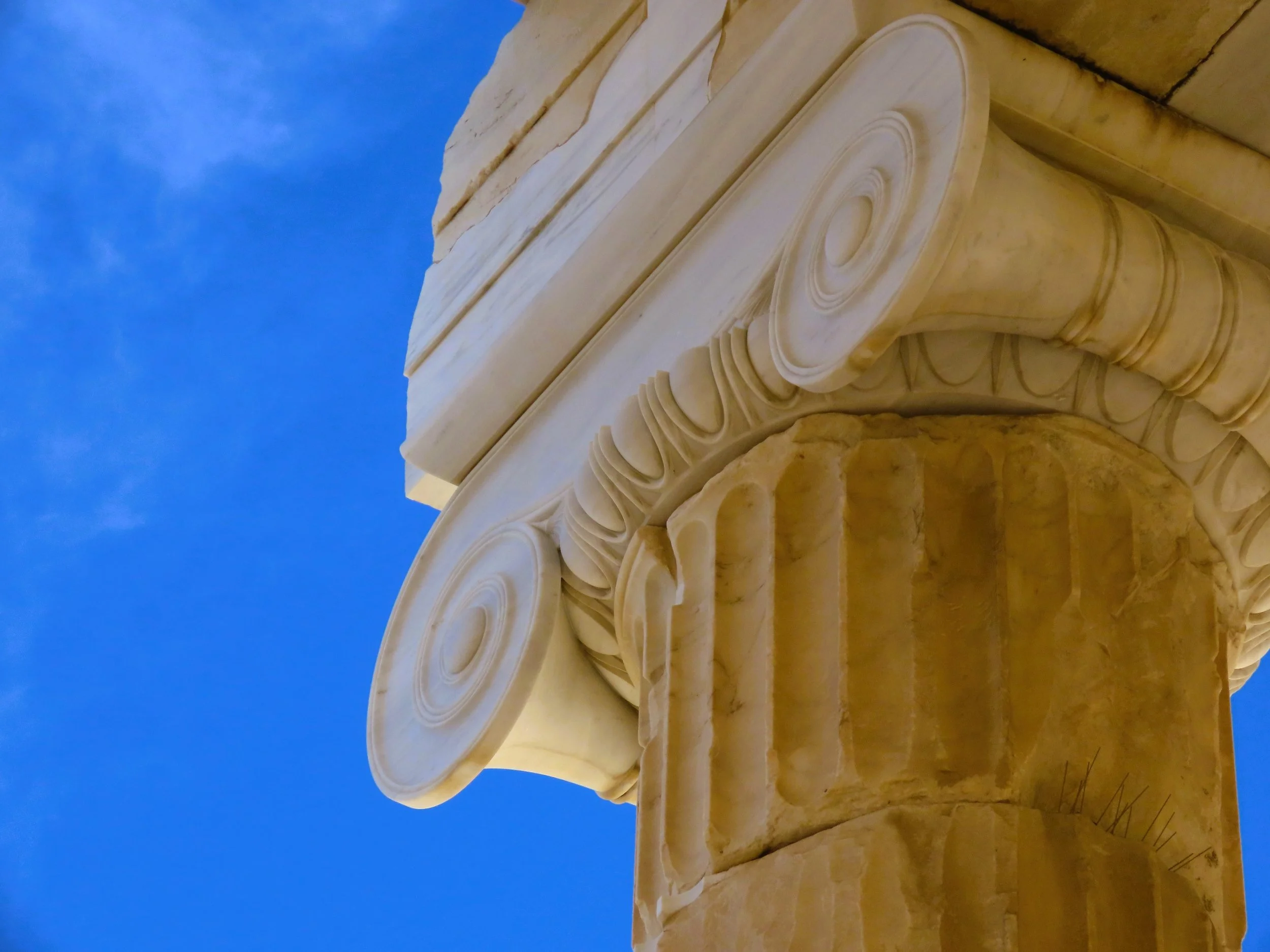 Colonna di stile classico con capitelli decorativi in marmo, contro uno sfondo di cielo azzurro