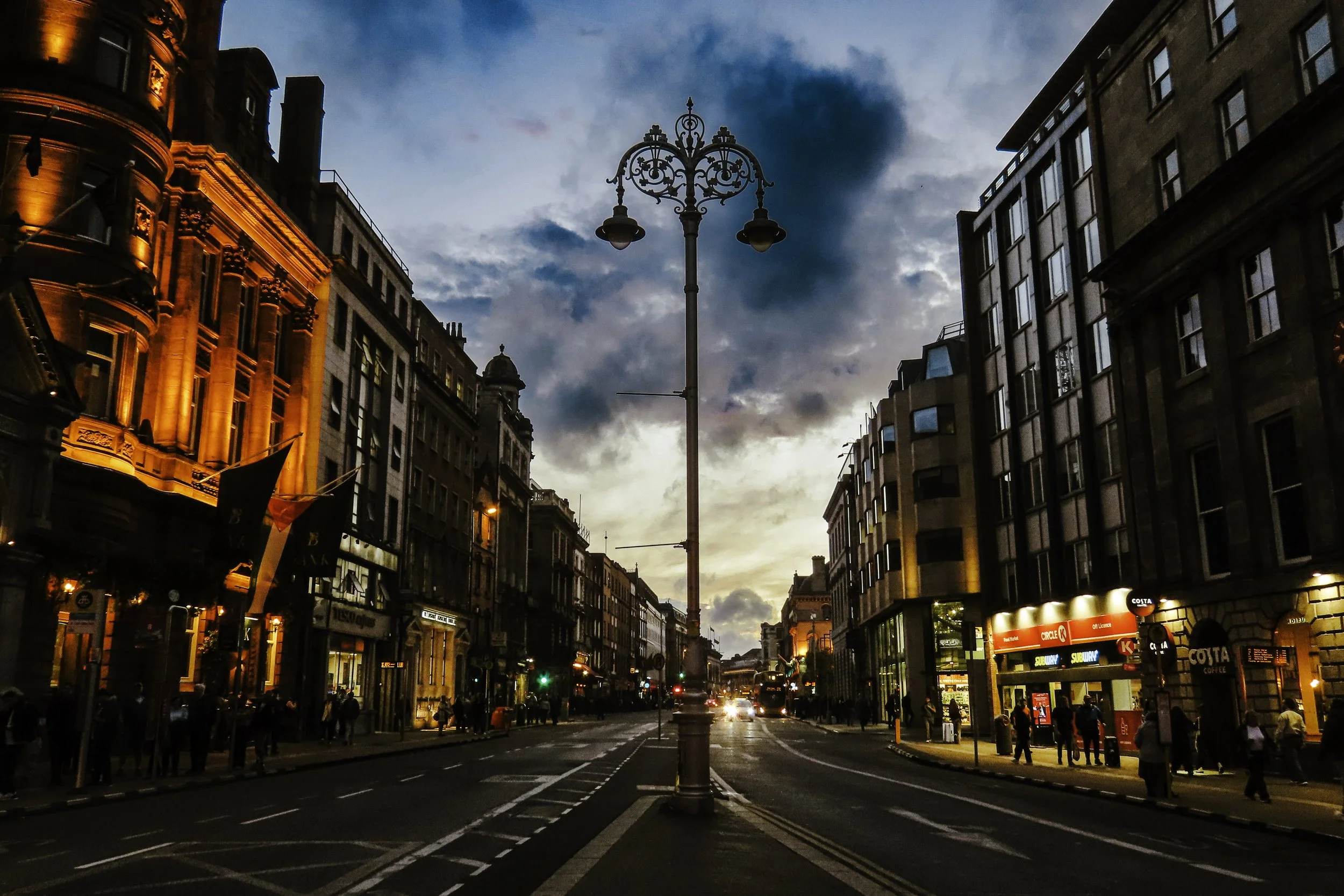 Veduta di una strada urbana con edifici illuminati al tramonto e un lampione al centro