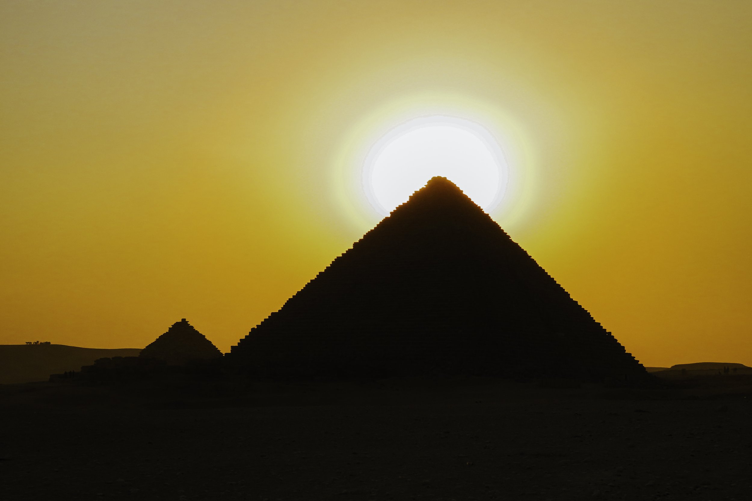 Le piramidi di Giza al tramonto con il sole dietro la piramide più grande.