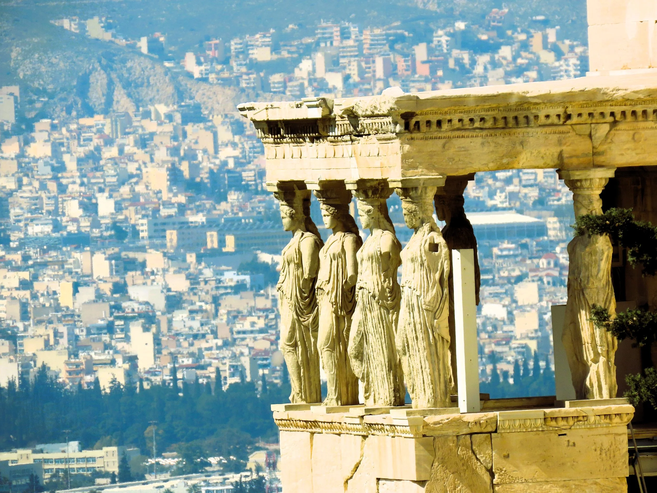 Particolare delle Caryatidi del Partenone sull'Acropoli di Atene, con una vista della città sullo sfondo.