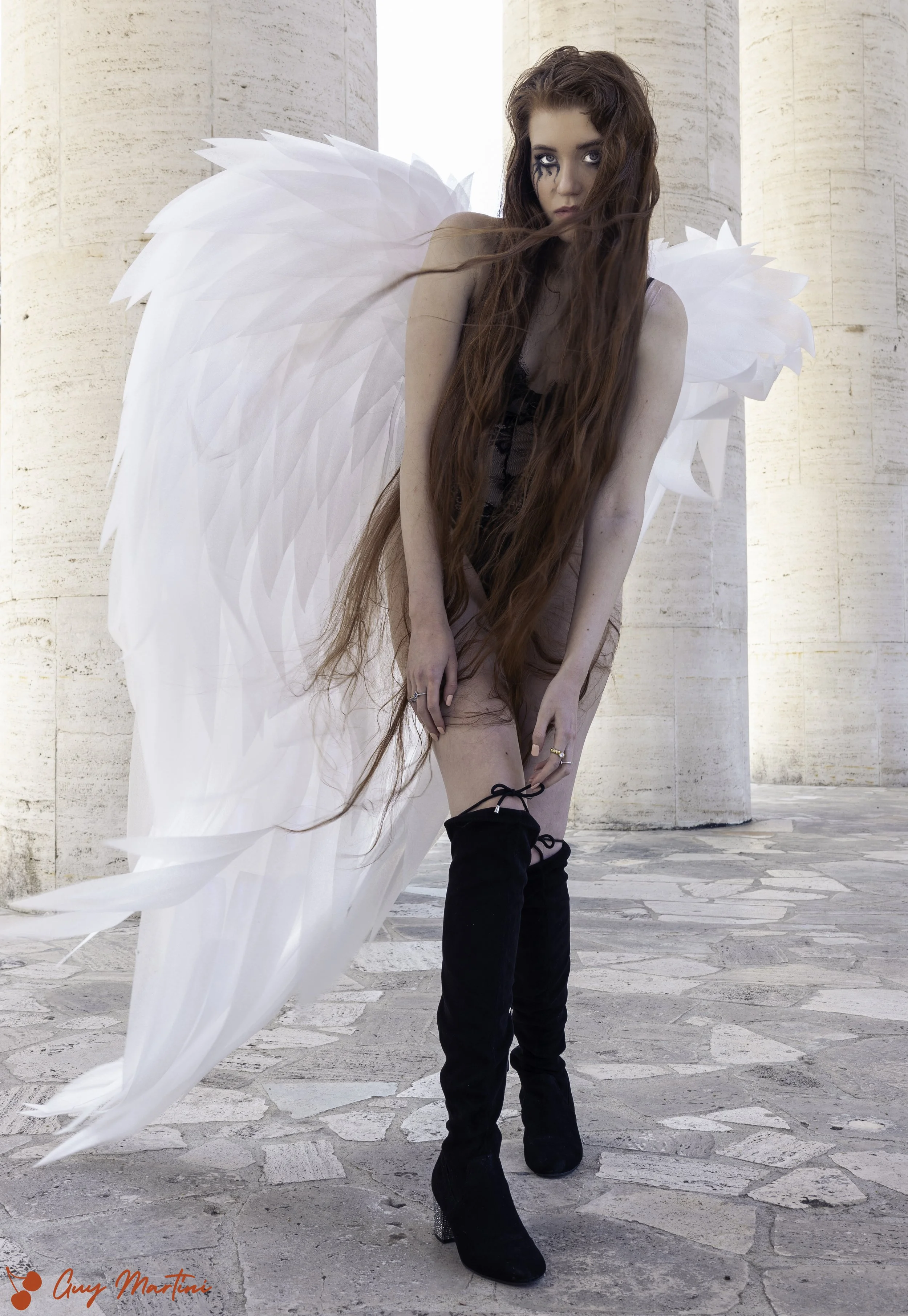 Donna con grandi ali bianche in un'ambientazione architettonica.