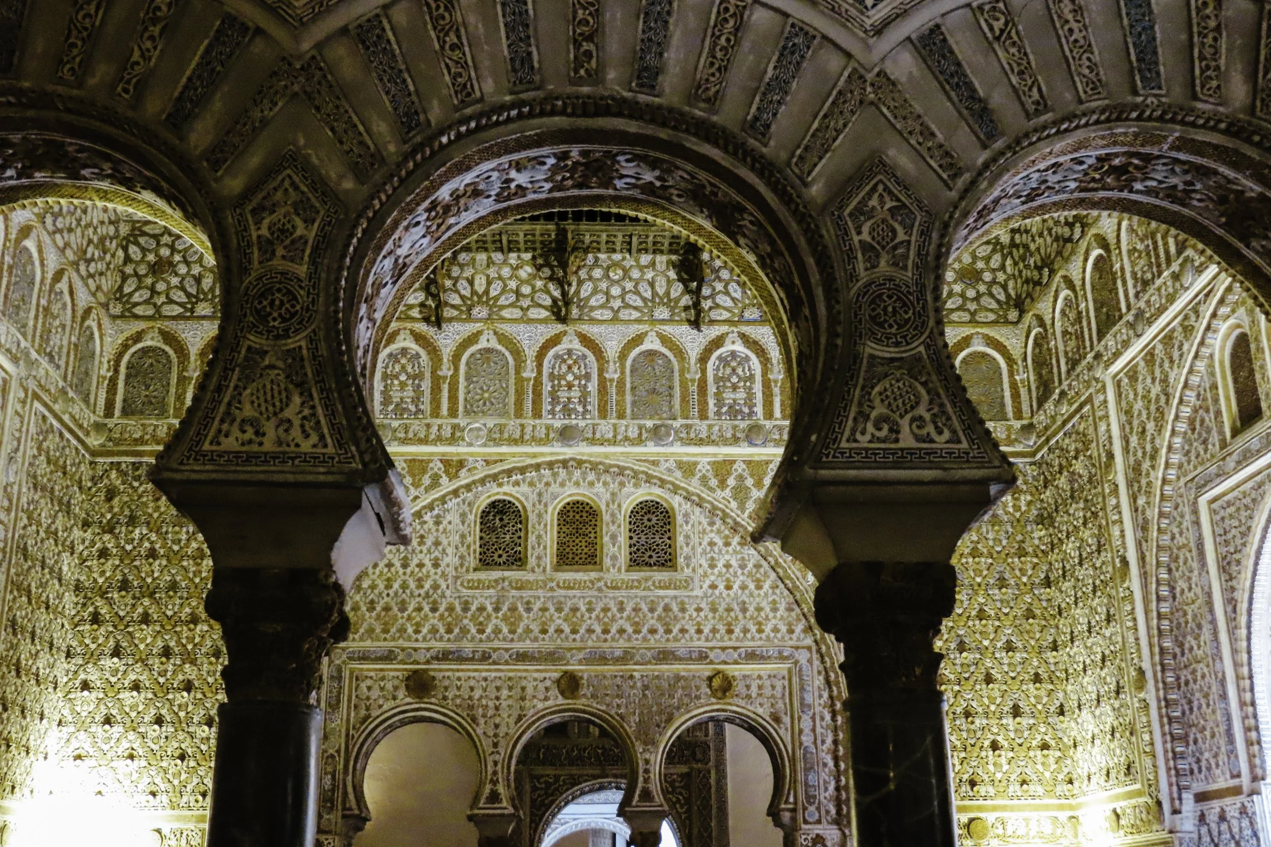 Interno di una struttura architettonica riccamente decorata con dettagli in oro, archi e colonne in stile moresco.