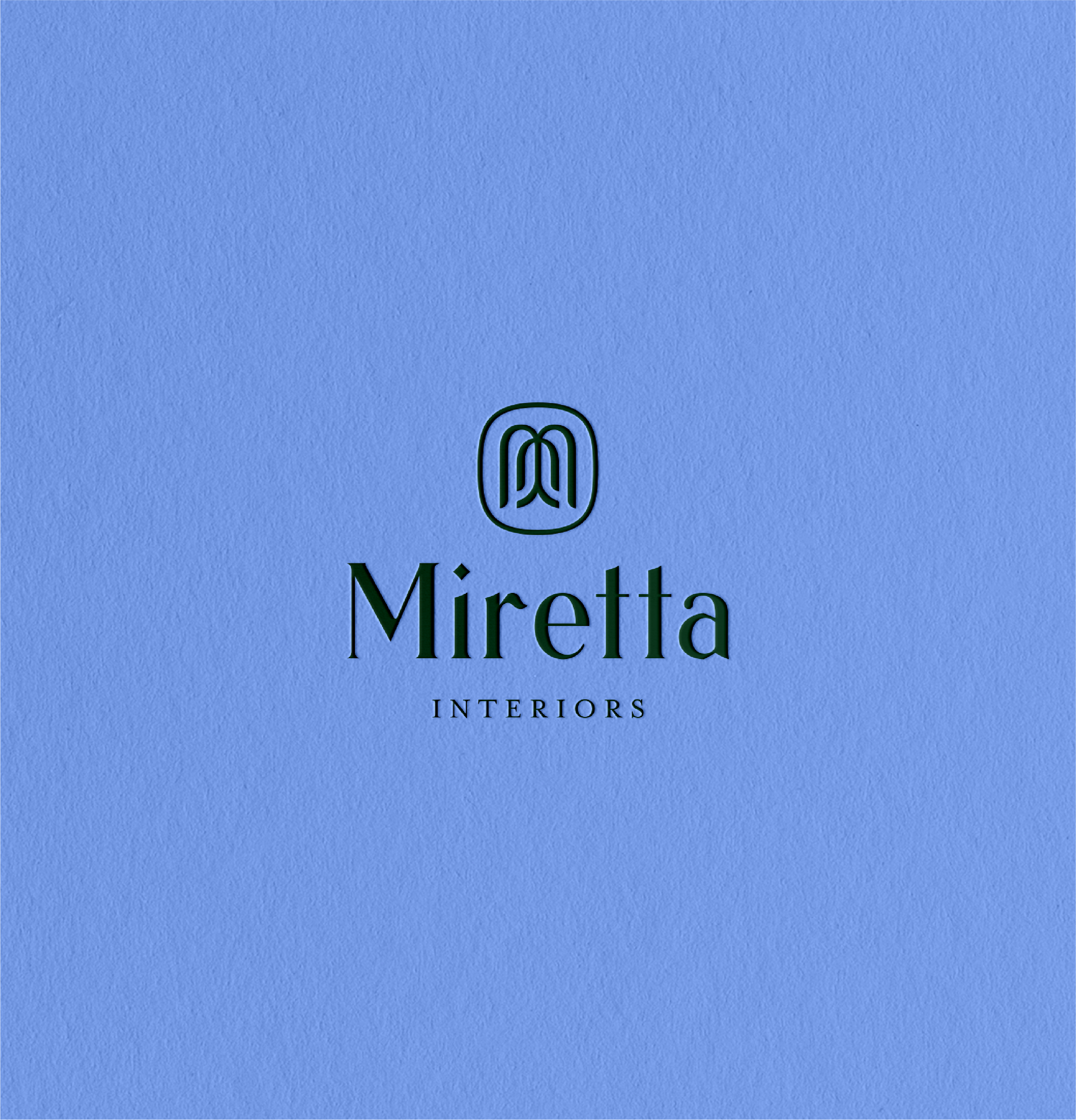 Blue background with a black outlined letter 'M' and the name 'Miratta' in black beneath it, followed by the word 'INTERIORS' in small black letters.