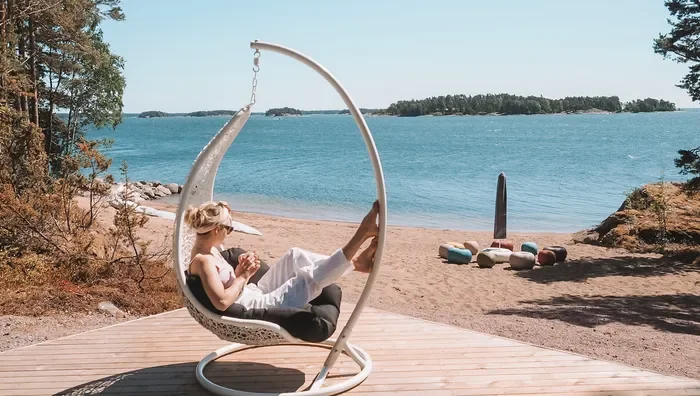 Woman practicing a seated yoga twist by an infinity pool overlooking the ocean at sunrise.