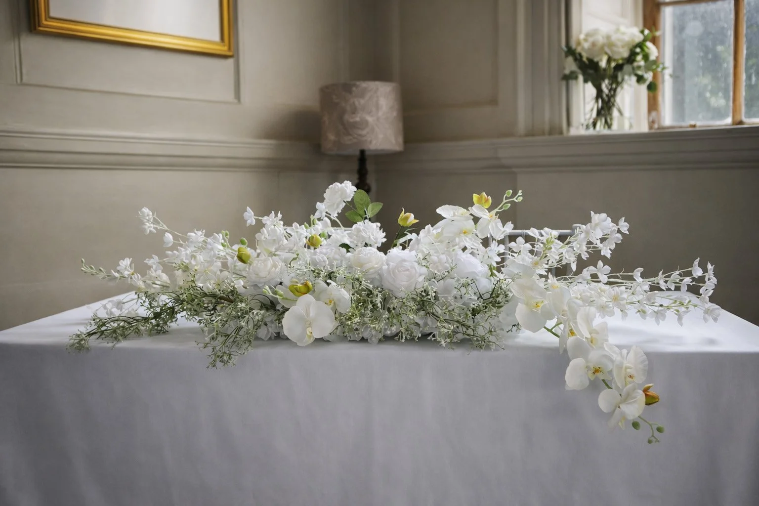 White and green Tiffany floral arrangement placed on a stone ledge for venue décor.