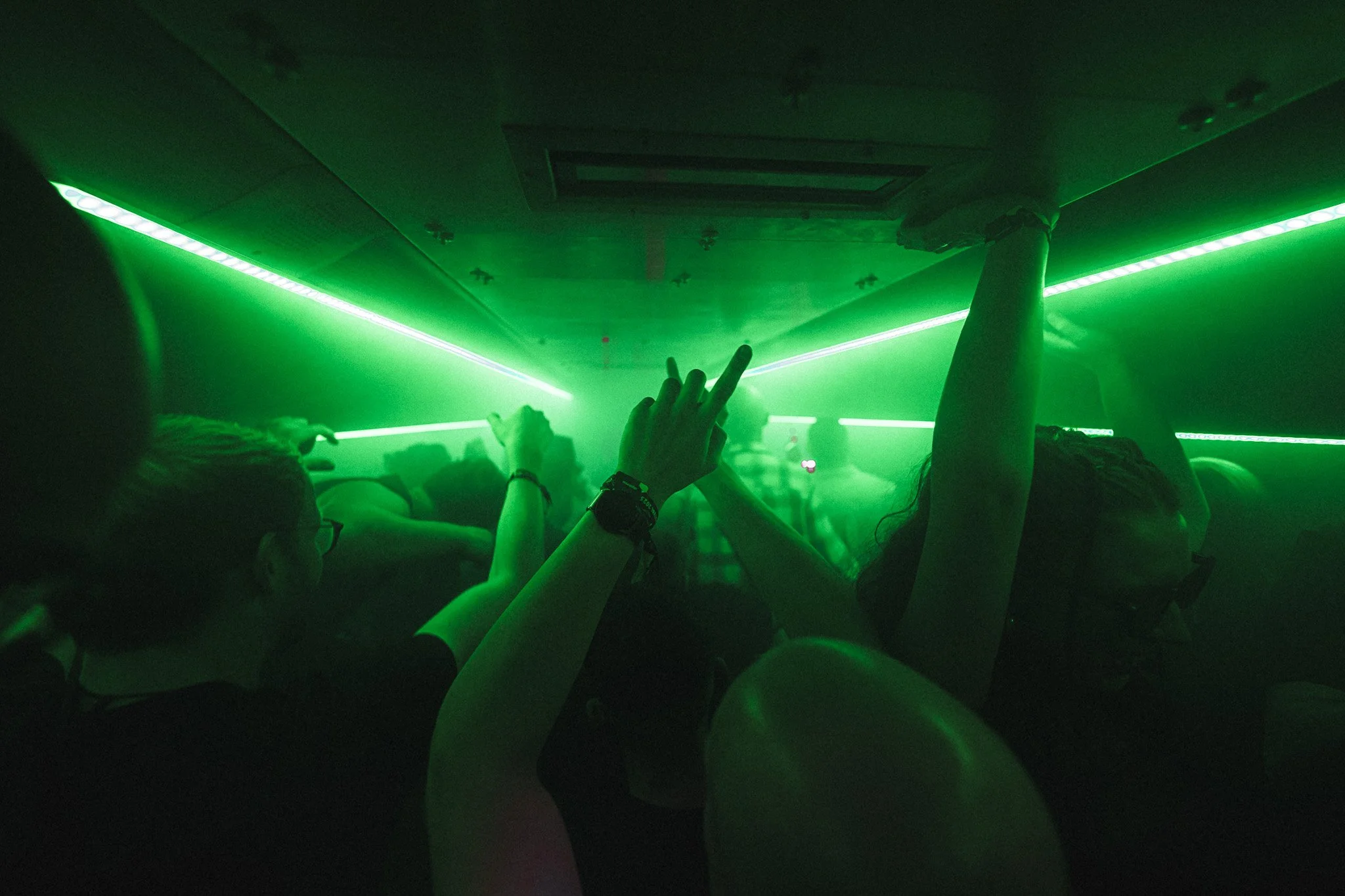 People dancing and enjoying a nightclub with green laser lights illuminating the room.