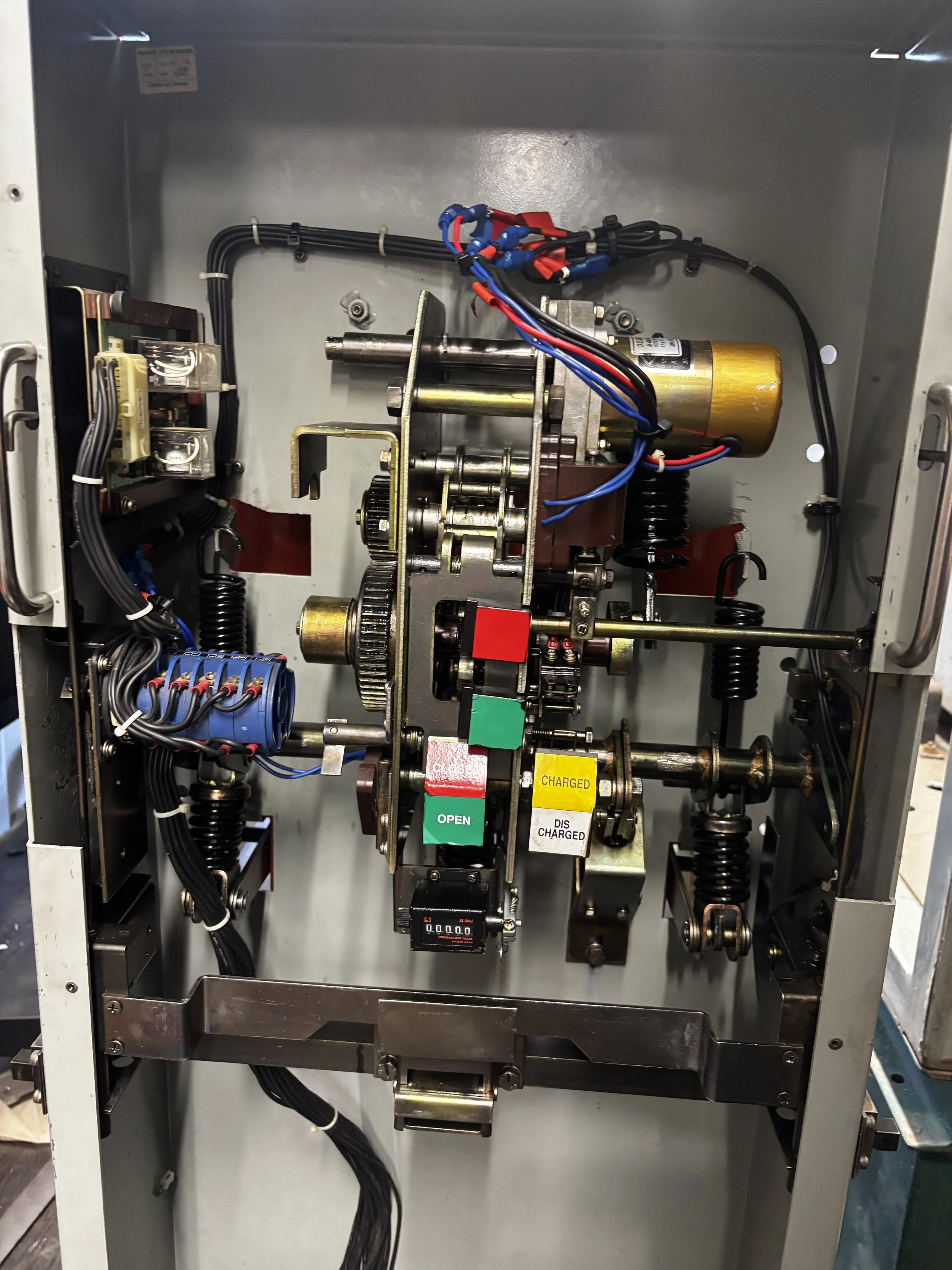 Close-up view of an industrial machine or electrical panel with wires, gears, and labeled switches.