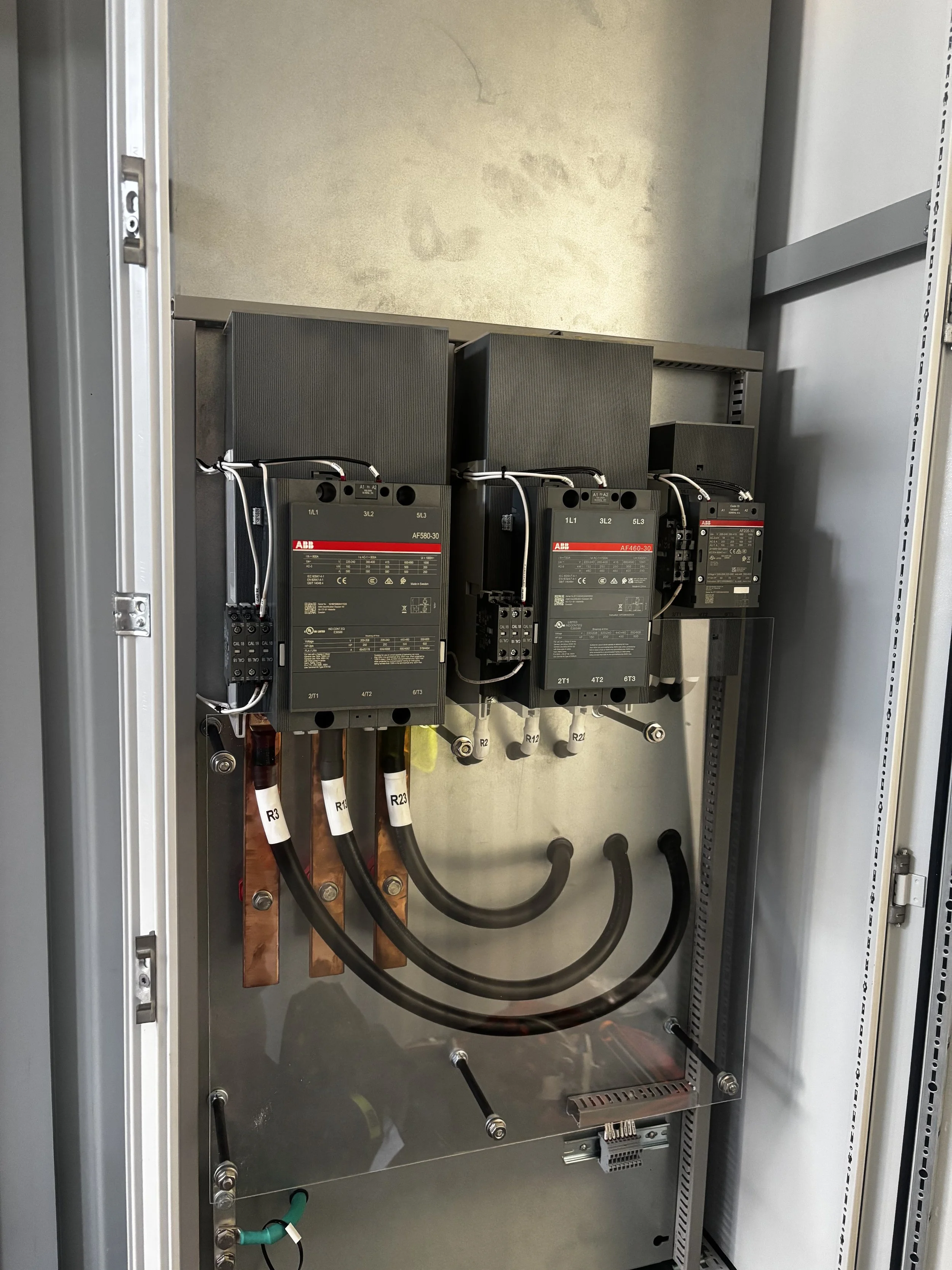 Inside an electrical control panel with three ABB motor starters, wiring, and copper bus bars.