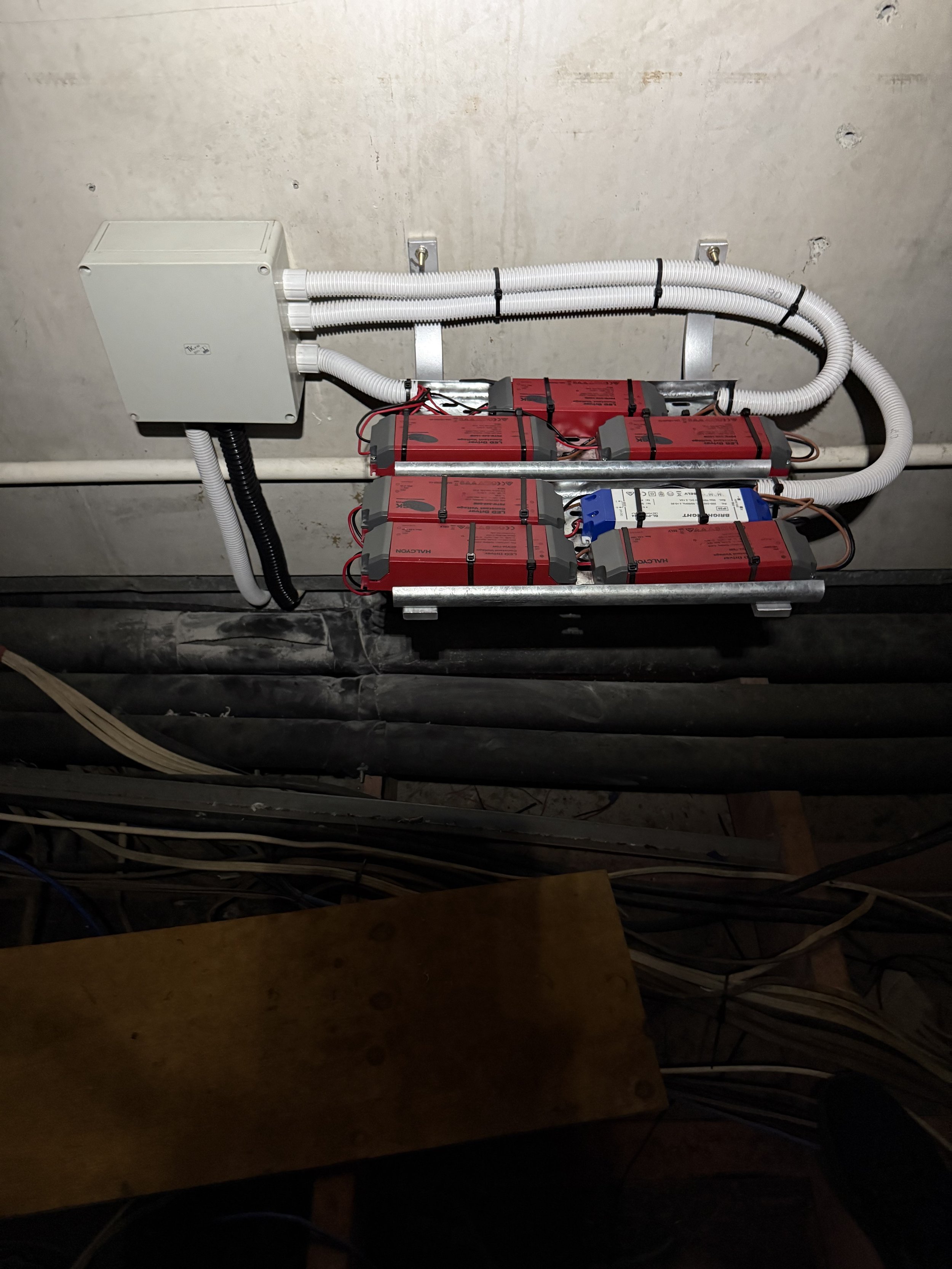 Electrical panel and batteries mounted on a wall with wiring and conduit.