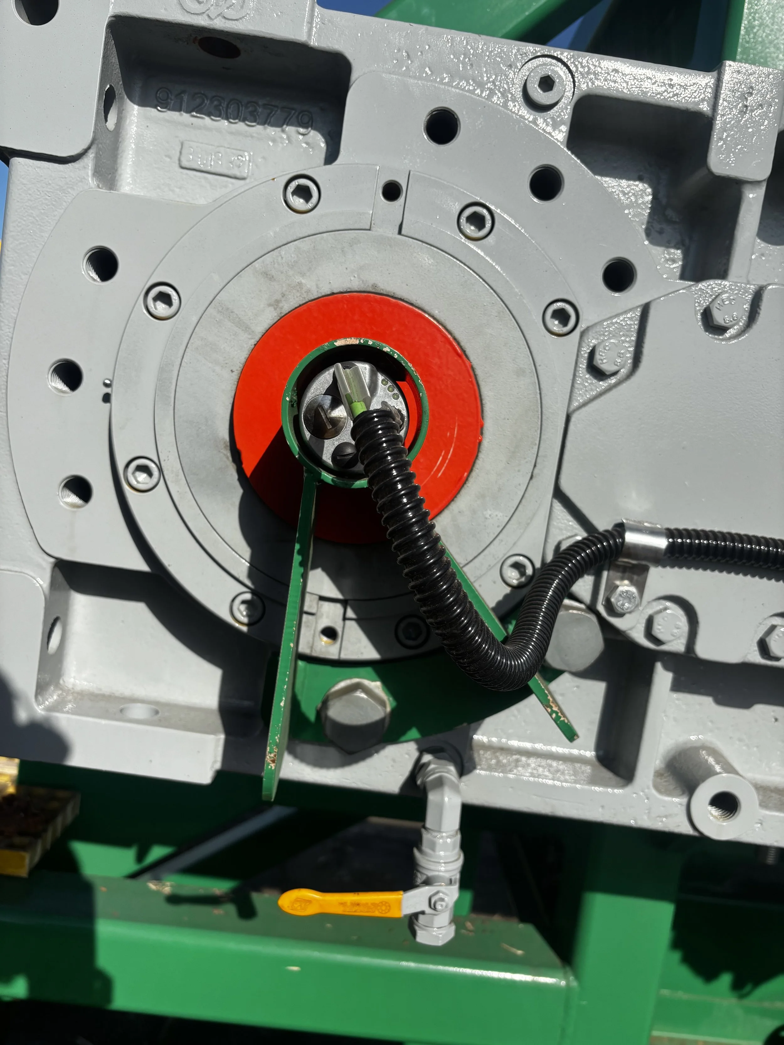 Close-up of a mechanical assembly with electrical wiring, bolts, and a red and green painted component, part of industrial machinery.