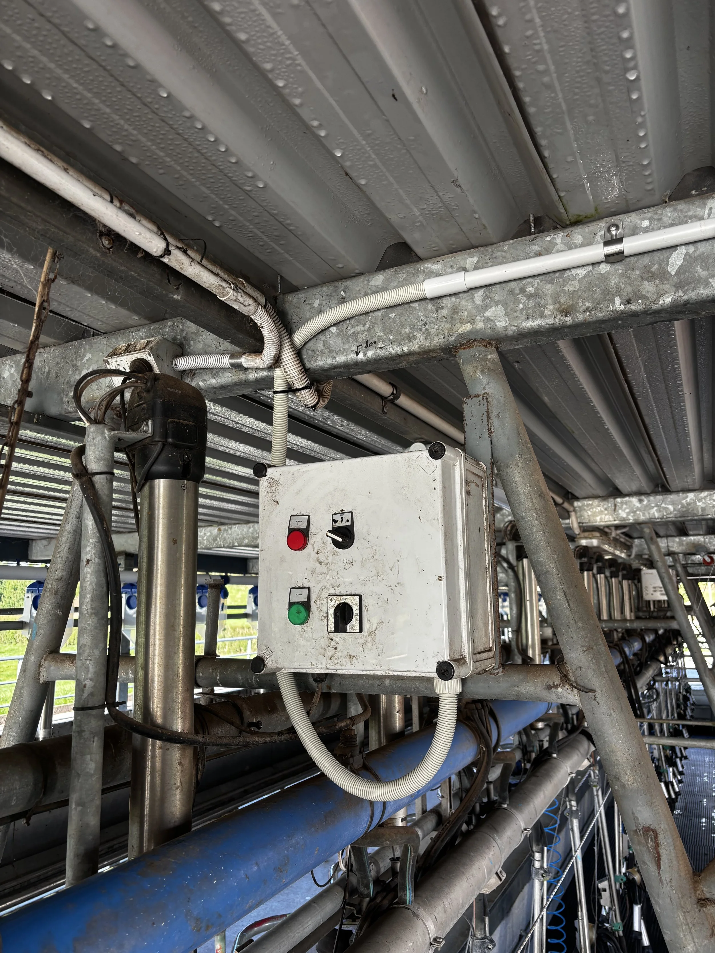 Close-up of industrial piping and electrical control box mounted on metal frame.