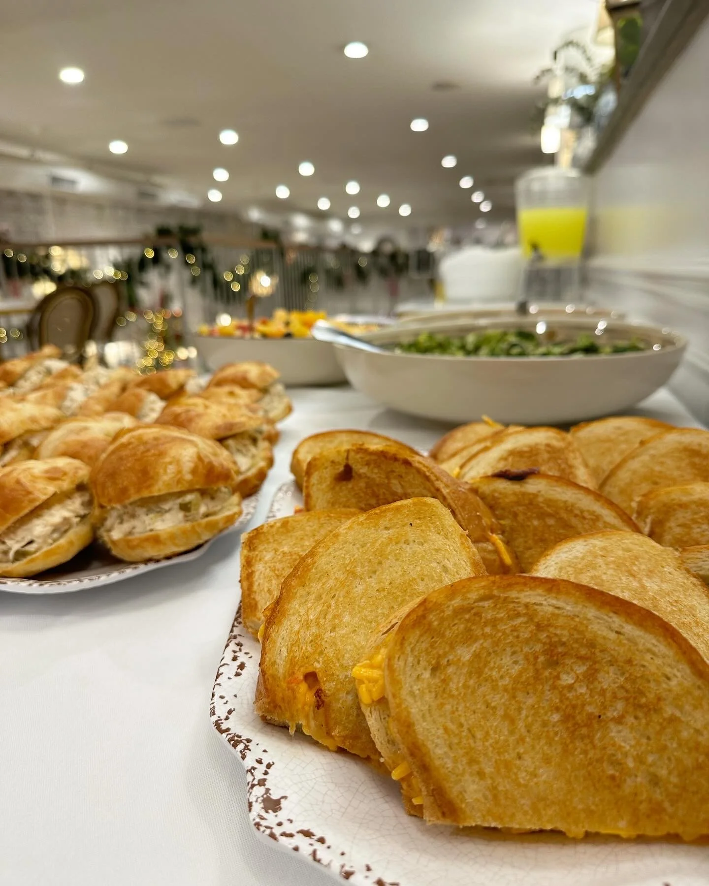 An assortment of sandwiches, chicken pot pie slices, salad, and a drink on a buffet table in a decorated room.