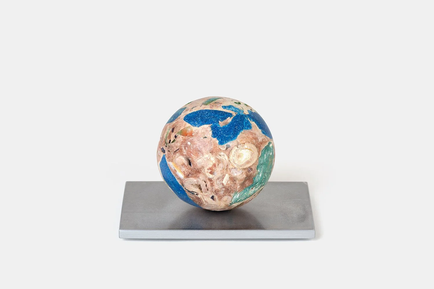 Yasue Maetake Orb Materia—Blue First Aid, 2026. Spherical form with strong blue mineral areas, warm beige surfaces, and embedded shell fragments, resting on a square aluminum base.