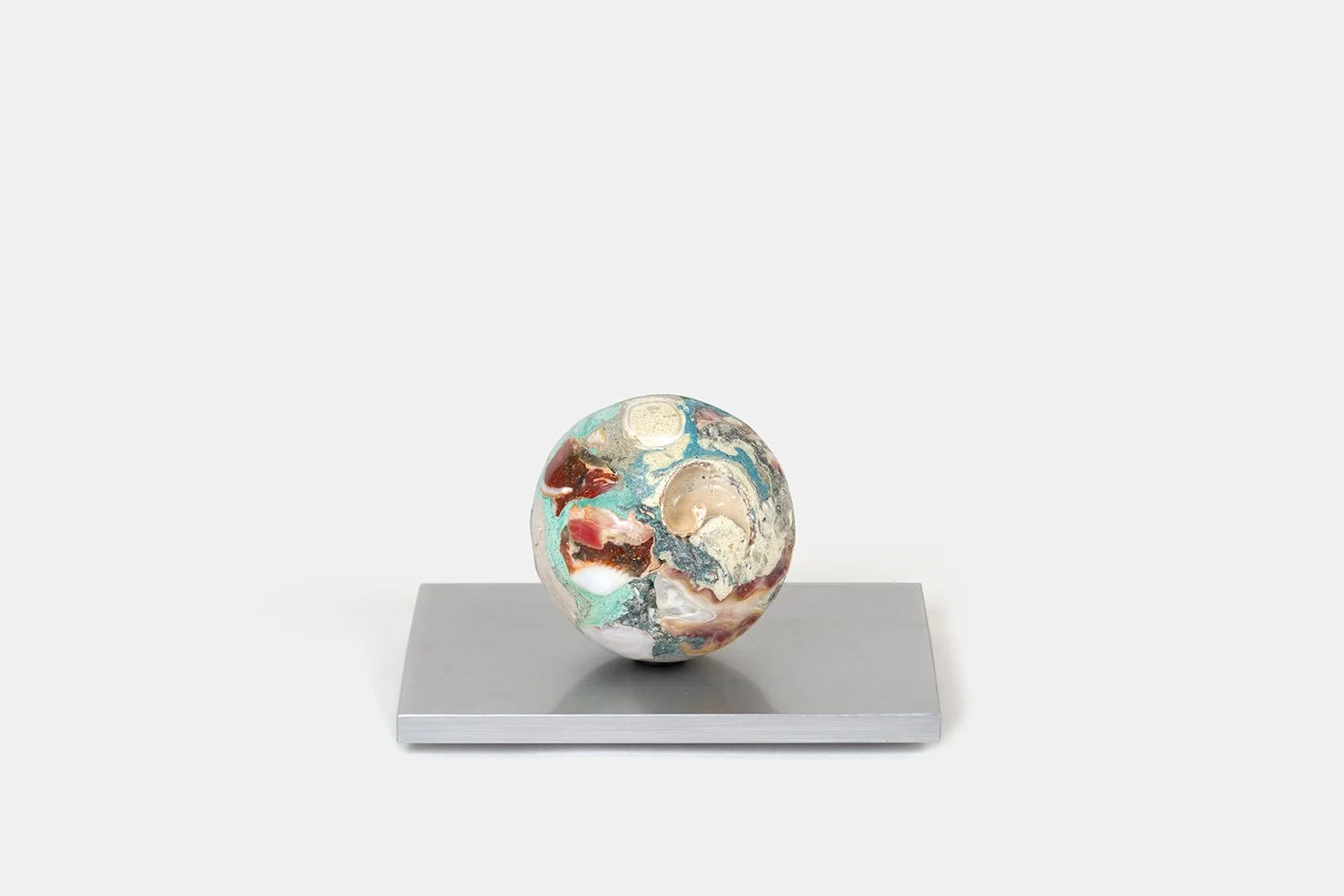 Yasue Maetake Orb Materia—Air Current, 2026. Spherical sculpture with turquoise, pink, and cream mineral surfaces containing shell fragments and open cavities, resting on a rectangular aluminum base.