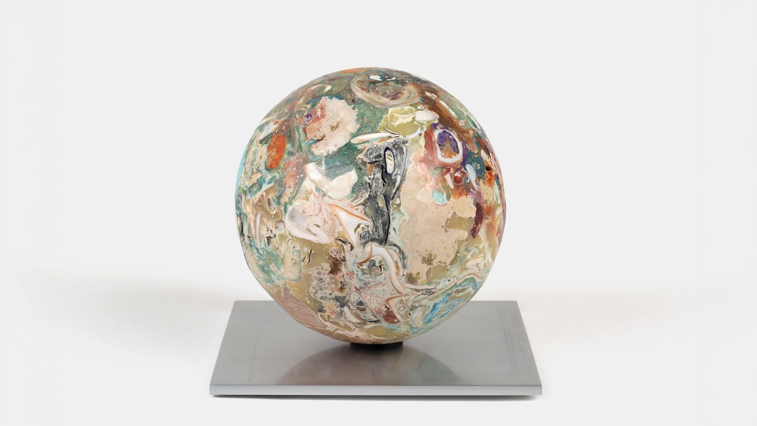 Orb Materia—Inlet-Swallowtail, 2026. Dense spherical form with layered shell fragments, turquoise, and multicolored mineral matter, resting on a square aluminum base.